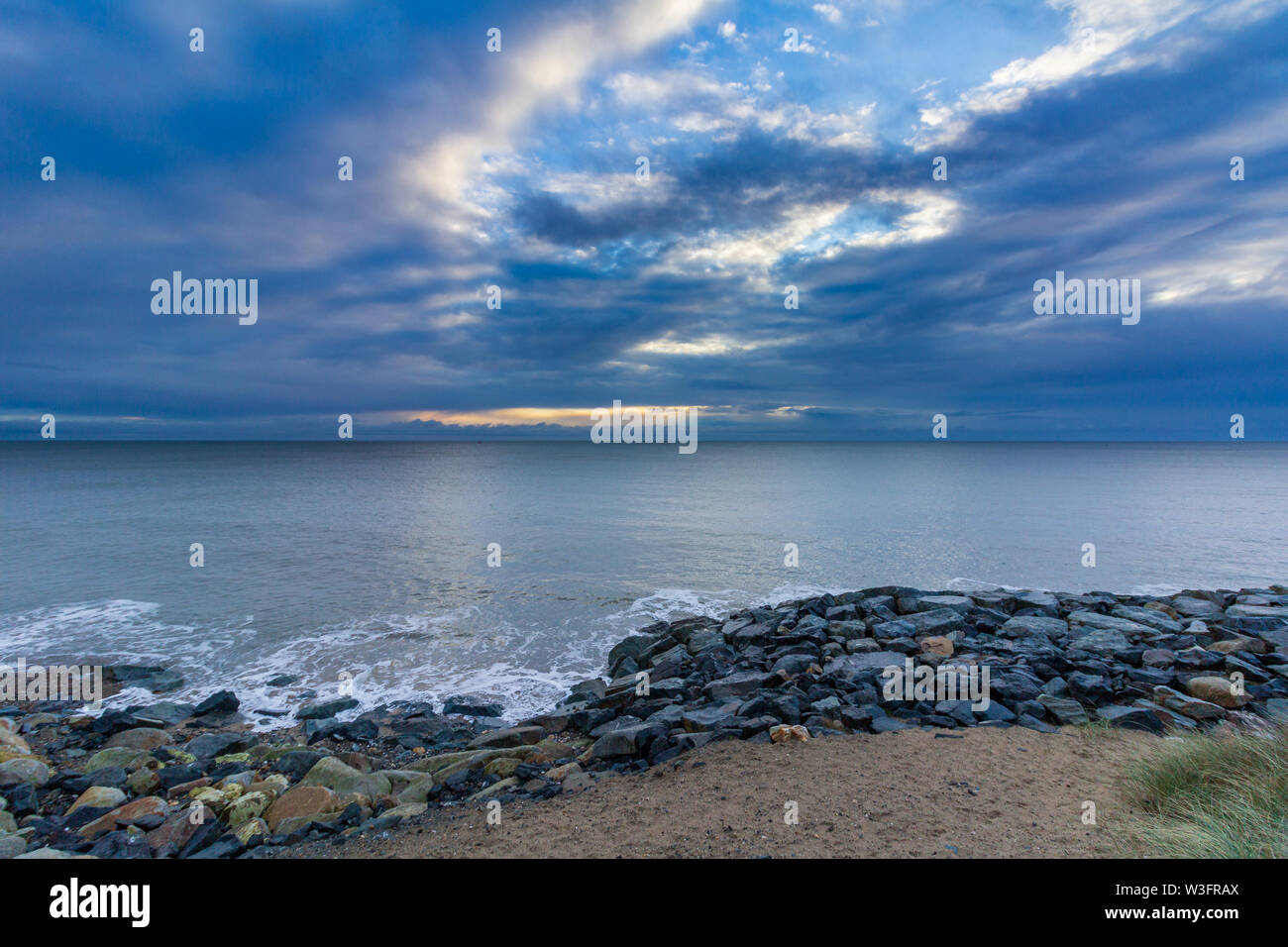 Sunrise a rocky Courtown Beach nella Contea di Wexford, Irlanda su un mattino nuvoloso Foto Stock