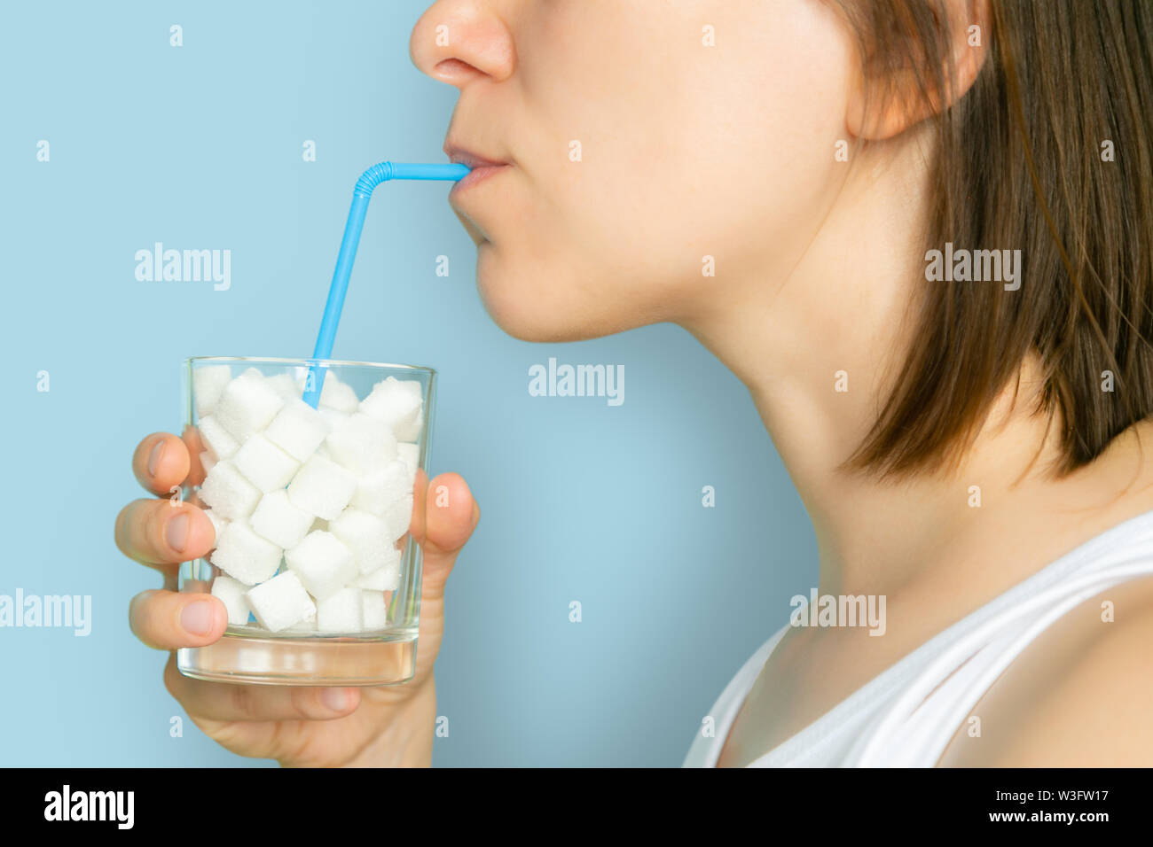 Eccessivo consumo di zucchero concetto - femmina bere dal bicchiere con cubetti di zucchero Foto Stock