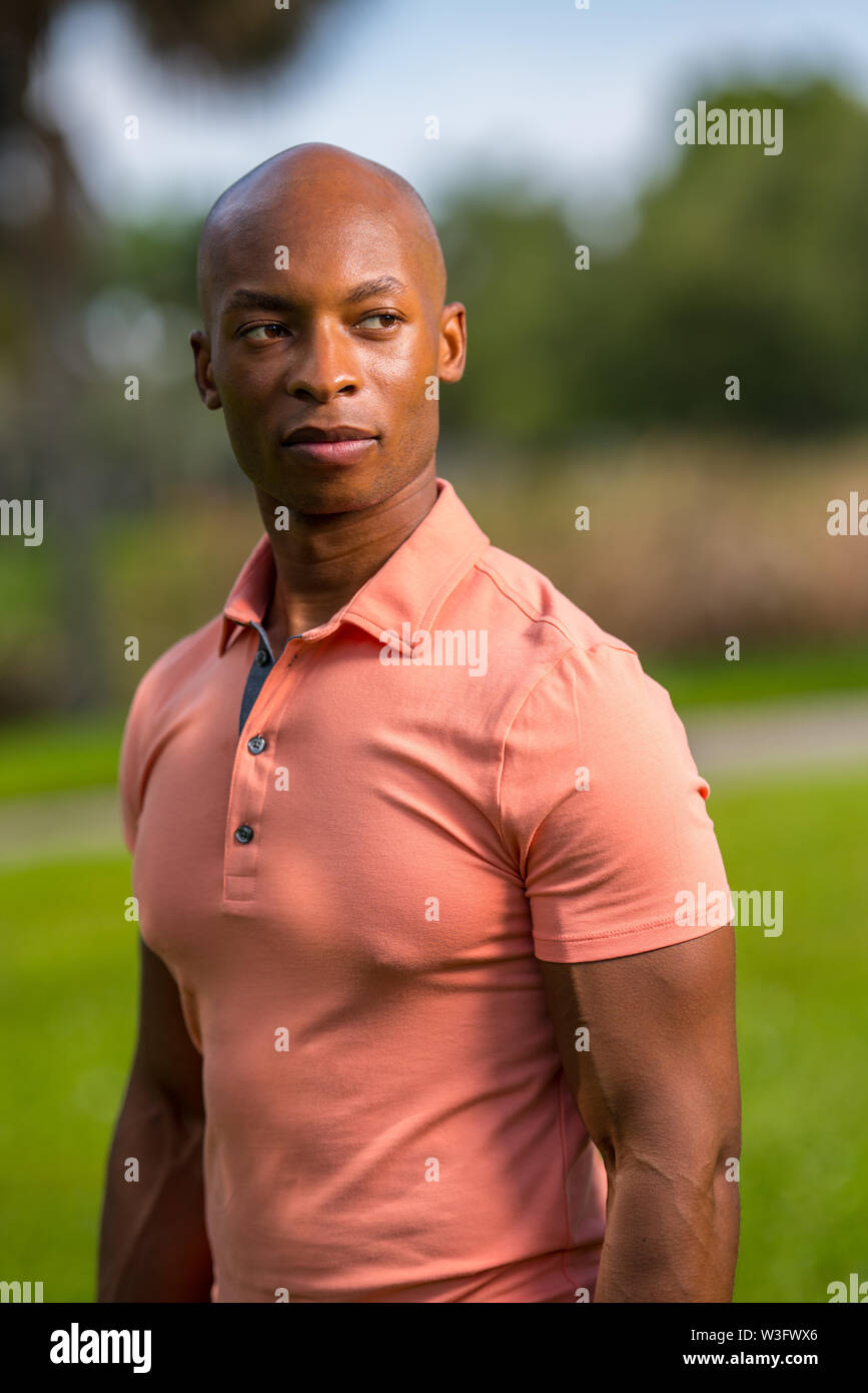 Ritratto di un bel americano africano uomo calvo che indossa un rosa polo shirt Foto Stock
