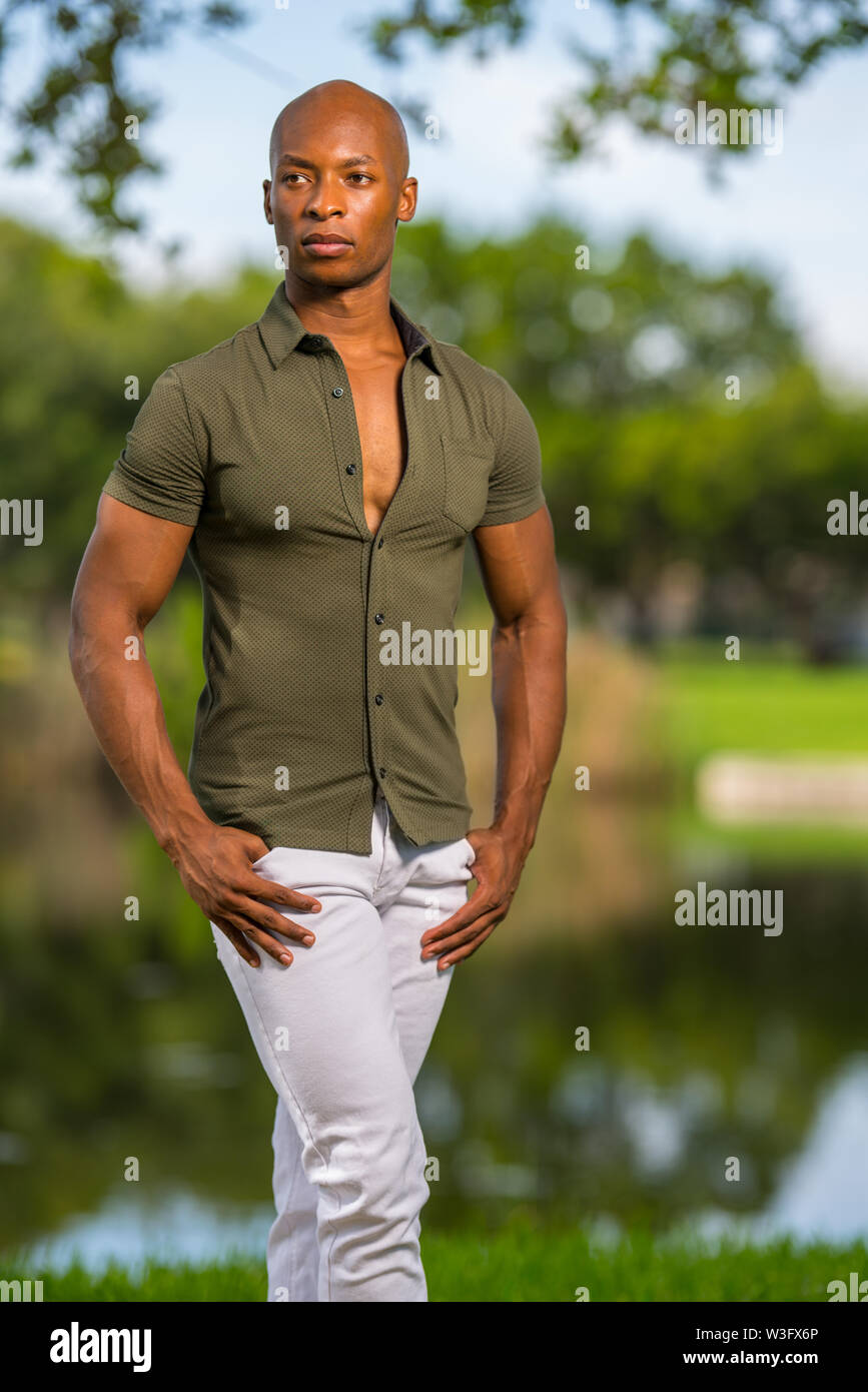 Foto di un uomo bello in posa con le mani nelle tasche in corrispondenza di una impostazione del parco Foto Stock