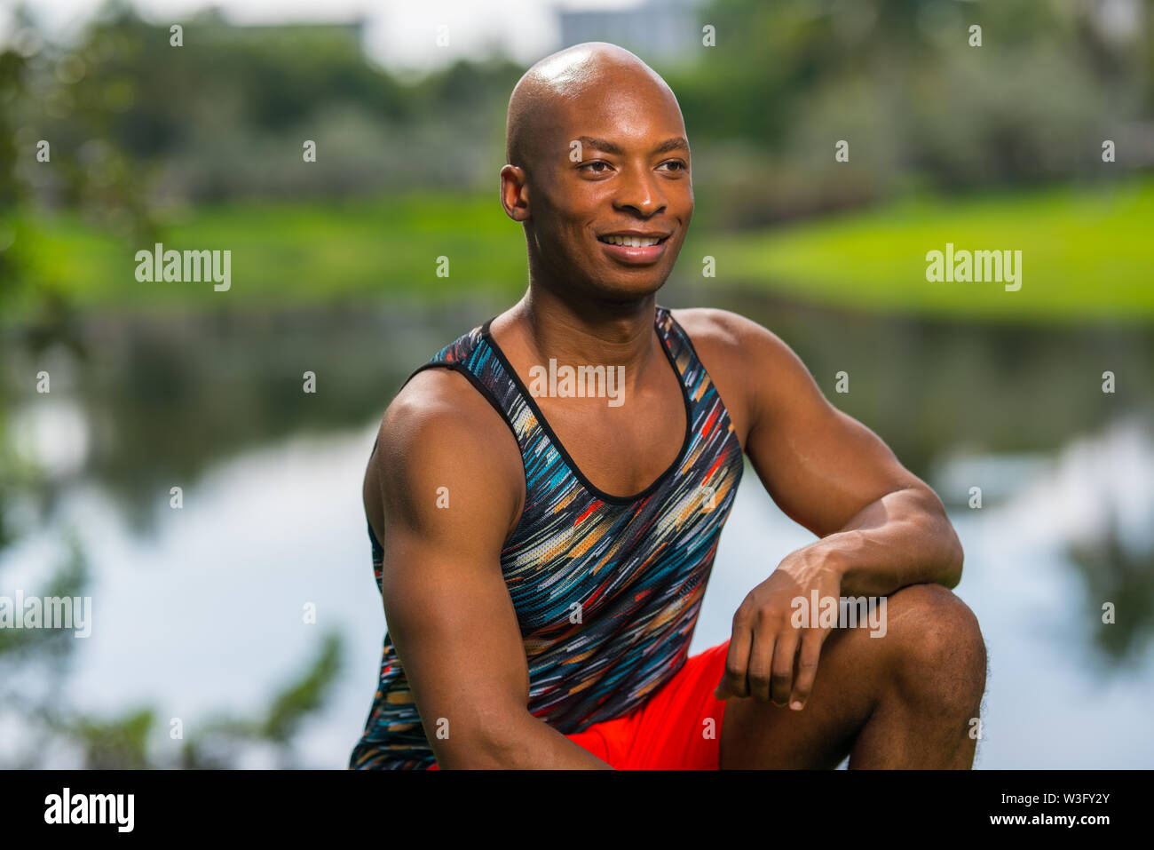 Felice giovane modello di fitness che pongono nel parco. Giovane americano africano maschio modello sorridente al di fuori della fotocamera. L'immagine illuminata con flash Foto Stock