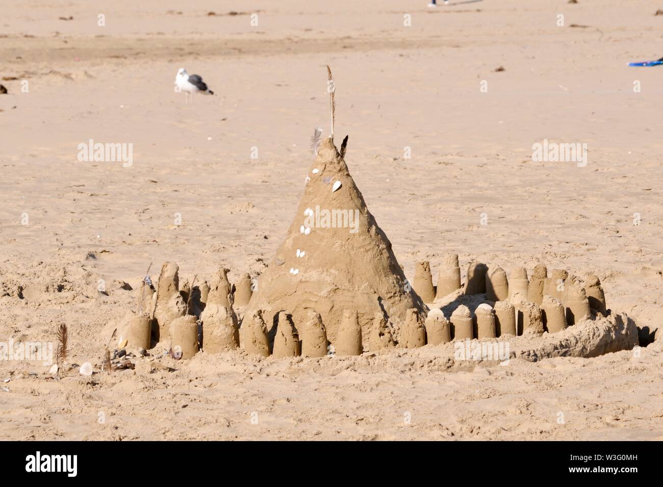Castello di sabbia sulla spiaggia di sabbia durante la luminosa giornata soleggiata con un gabbiano in piedi di distanza, CALIFORNIA, STATI UNITI D'AMERICA Foto Stock