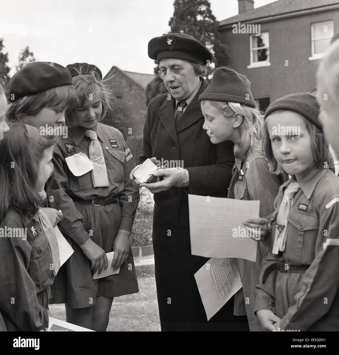 1967, storico gruppo di Coccinelle e giovane ragazza guide essendo mostrata una medaglia di guida da un senior ragazza guida, un premio per la sua lunga e un servizio eccezionale per l'organizzazione. La ragazza Guide è stata fondata nel 1910 per incoraggiare le ragazze ad essere i migliori possono essere e diventare sicuri delle donne. Foto Stock