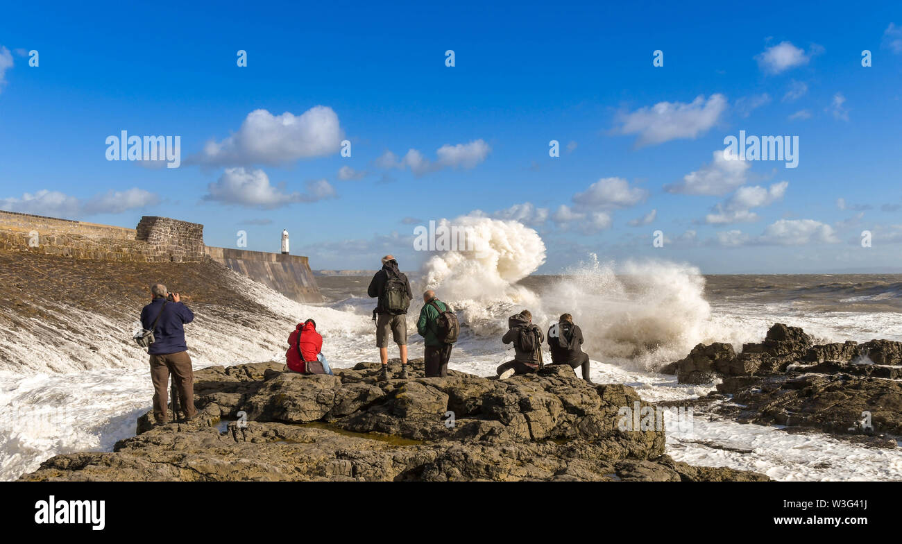 PORTHCAWL, EALES - Ottobre 2018: gruppo di persone sulle rocce a scattare foto di grandi onde sulla marea. Foto Stock