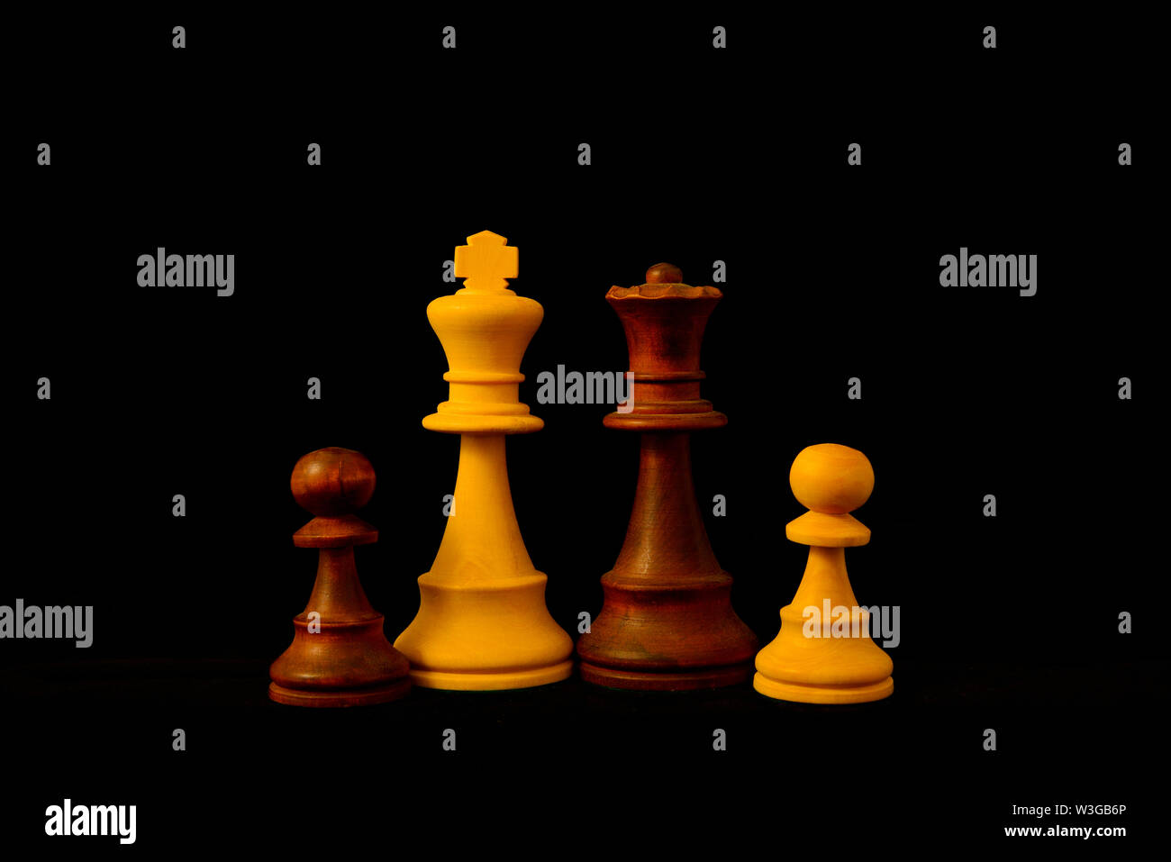 Re bianco, nero la regina e il pedone misti come concetto di famiglia.Standard del gioco degli scacchi pezzi di legno su sfondo nero Foto Stock