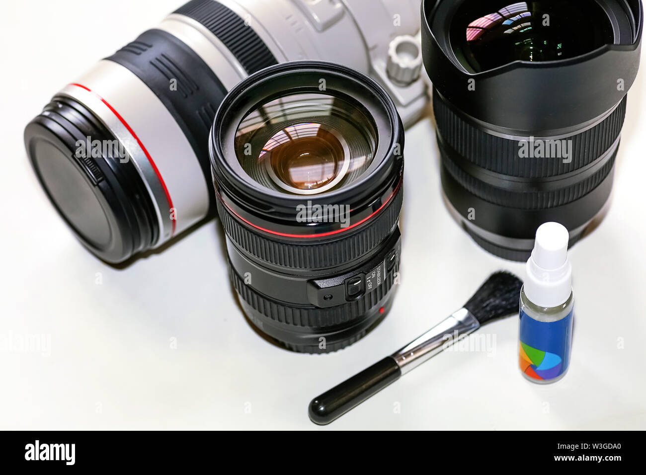 Lenti della fotocamera sul display da Canon 100-400mm teleobiettivo con zoom di Tamron 15-30mm ultra grandangolo con kit di pulizia su sfondo bianco Foto Stock