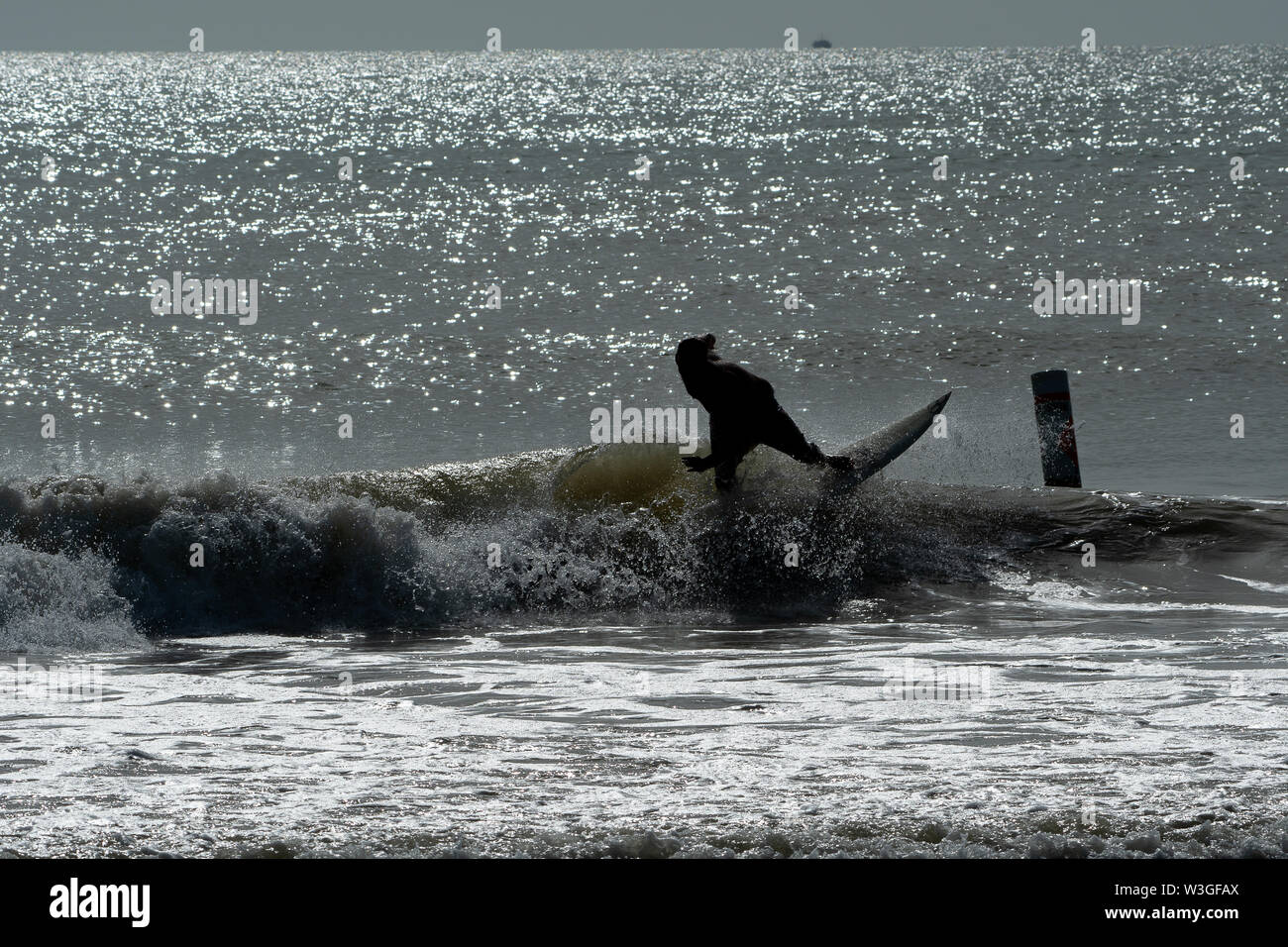 Silhouette di un surfista cavalcare le onde al tramonto in Florida Foto Stock