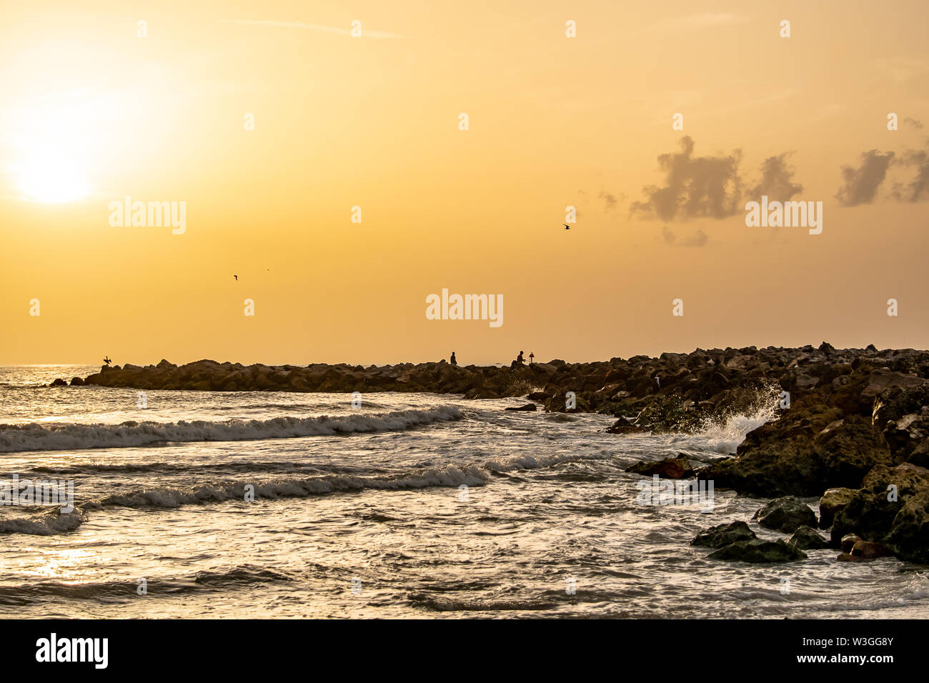 Paesaggio spiaggia al tramonto con rocce e onde in estate Foto Stock