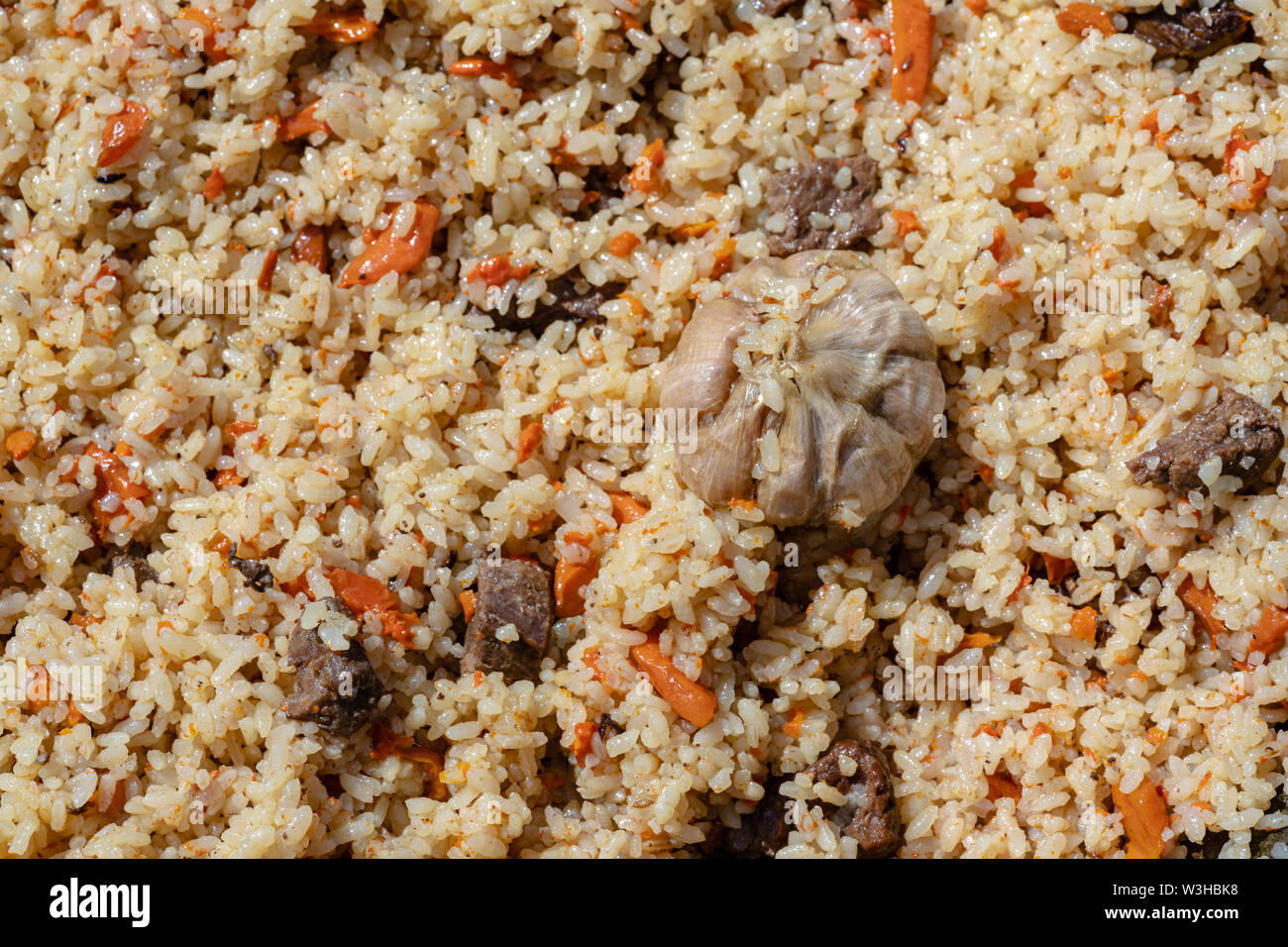 Tradizionale culinaria orientale piatto - pilaf. Ingredienti: riso con fette di carne, grasso e verdure (carota, aglio), spezie - ricetta popolare. Chiudere- Foto Stock