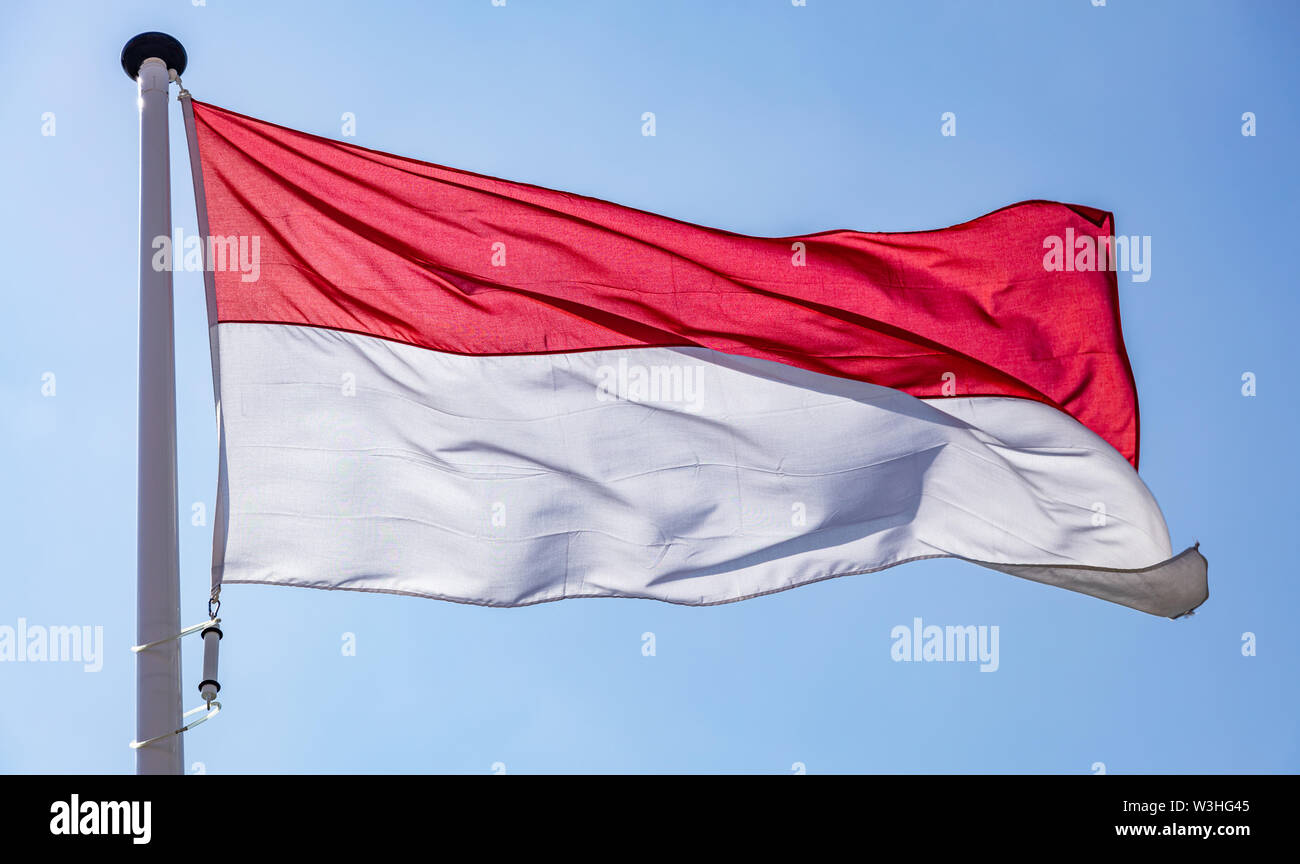 Bandiera dell'Indonesia, indonesiano simbolo nazionale sventolare contro il cielo blu chiaro, giornata di sole Foto Stock