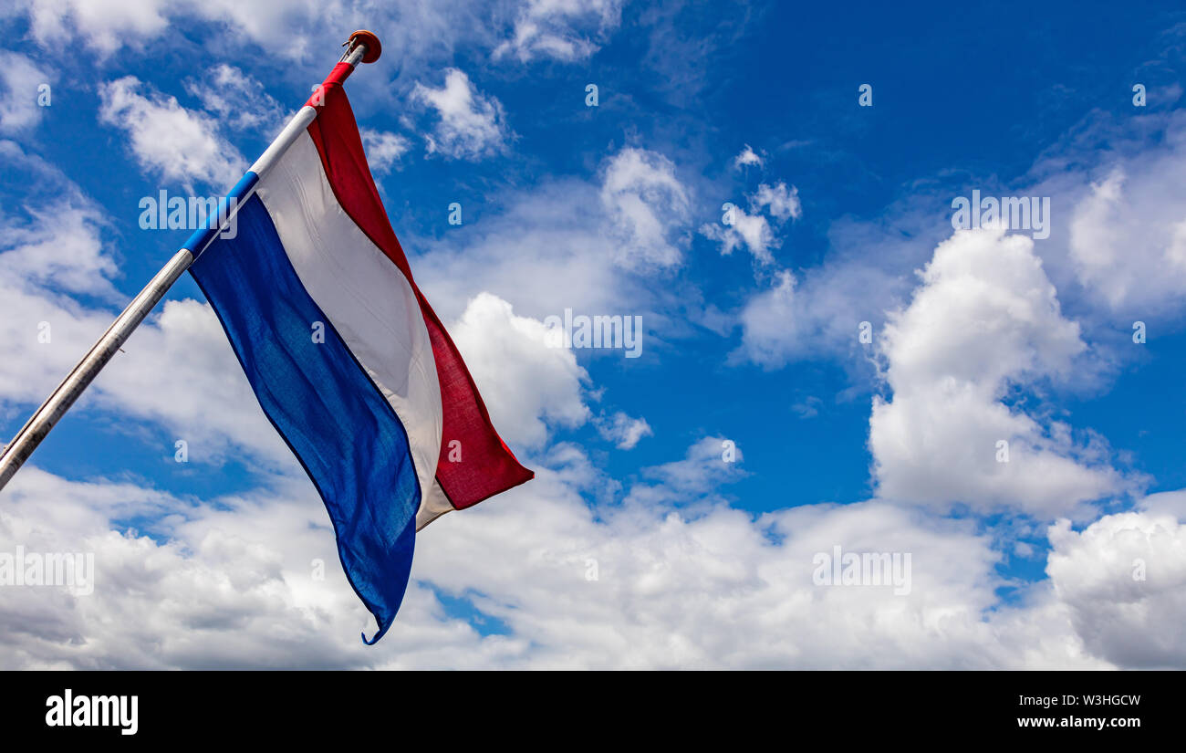 Bandiera dei Paesi Bassi. Dutch simbolo nazionale sventolare sul giorno della liberazione contro il cielo blu con nuvole, giornata di sole, spazio di copia Foto Stock