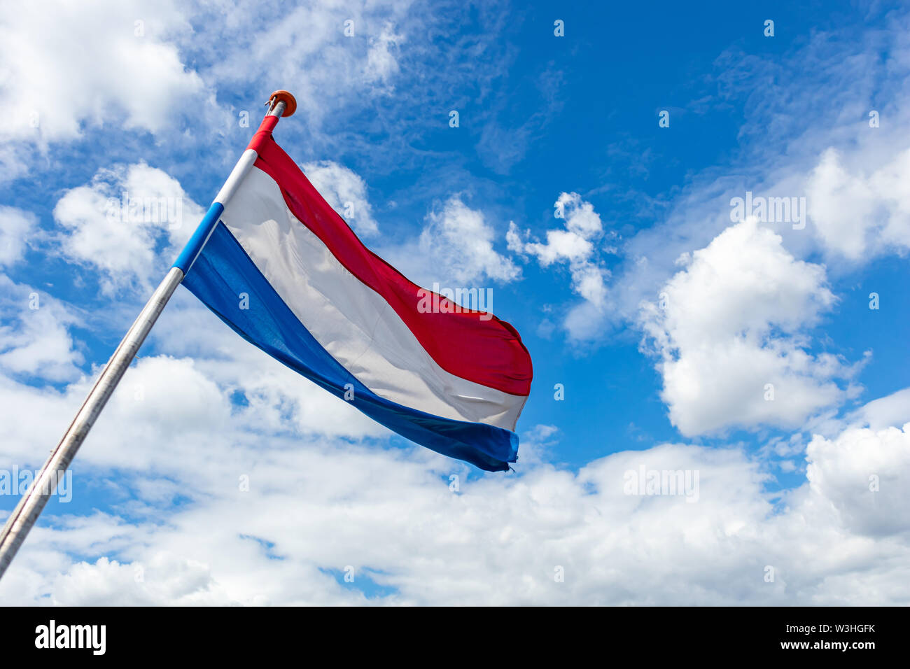 Bandiera dei Paesi Bassi. Dutch simbolo nazionale sventolare sul giorno della liberazione contro il cielo blu con nuvole, giornata di sole, spazio di copia Foto Stock