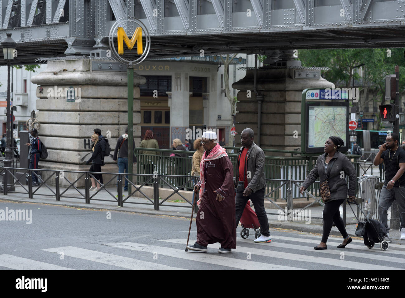 Le persone che attraversano le street in red semaforo alla stazione Metro Barbès Rochechouart, Parigi, Francia Foto Stock