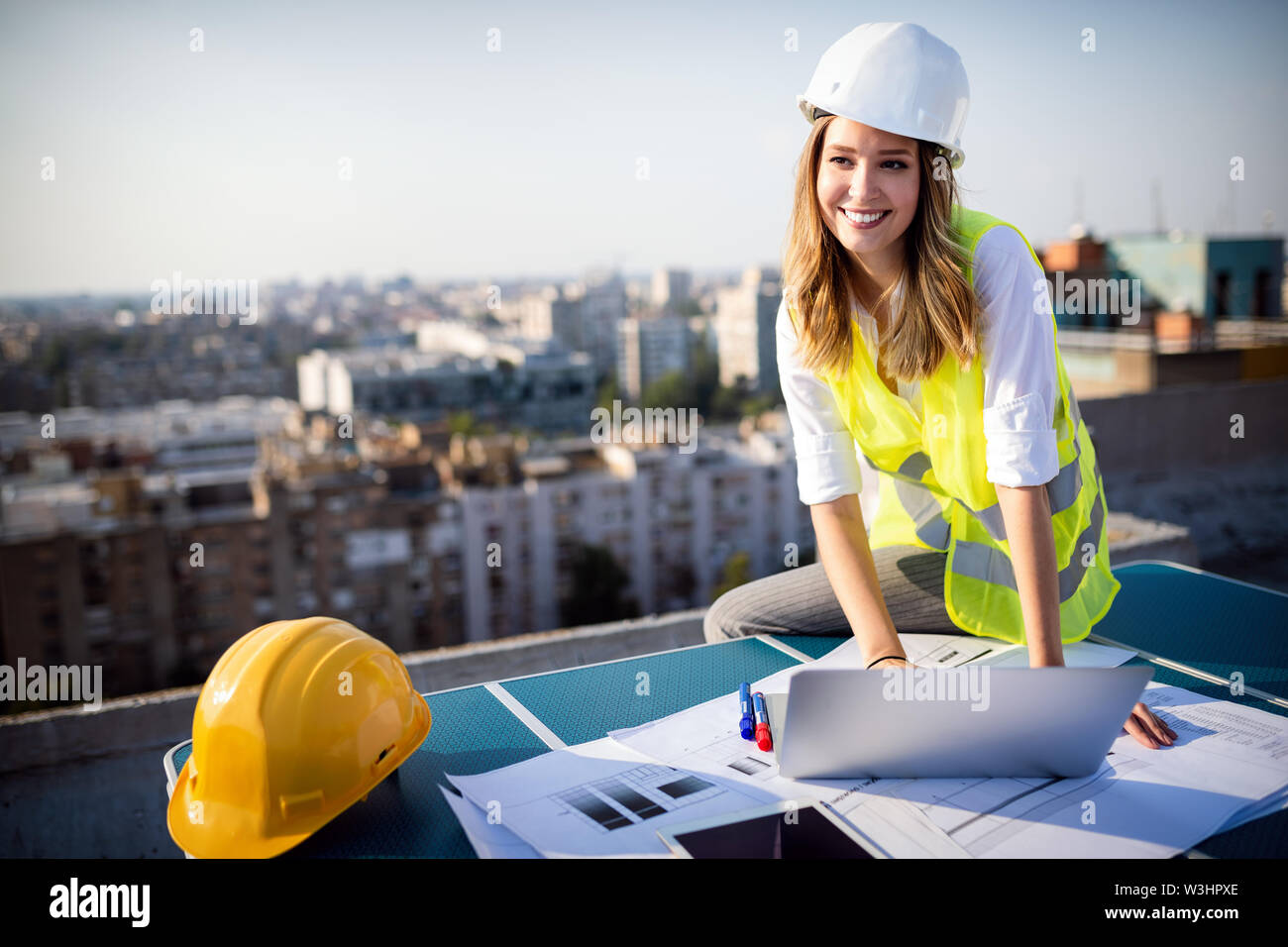 Giovani femmine costruzione ingegnere specializzato rivedendo blueprint al sito in costruzione Foto Stock