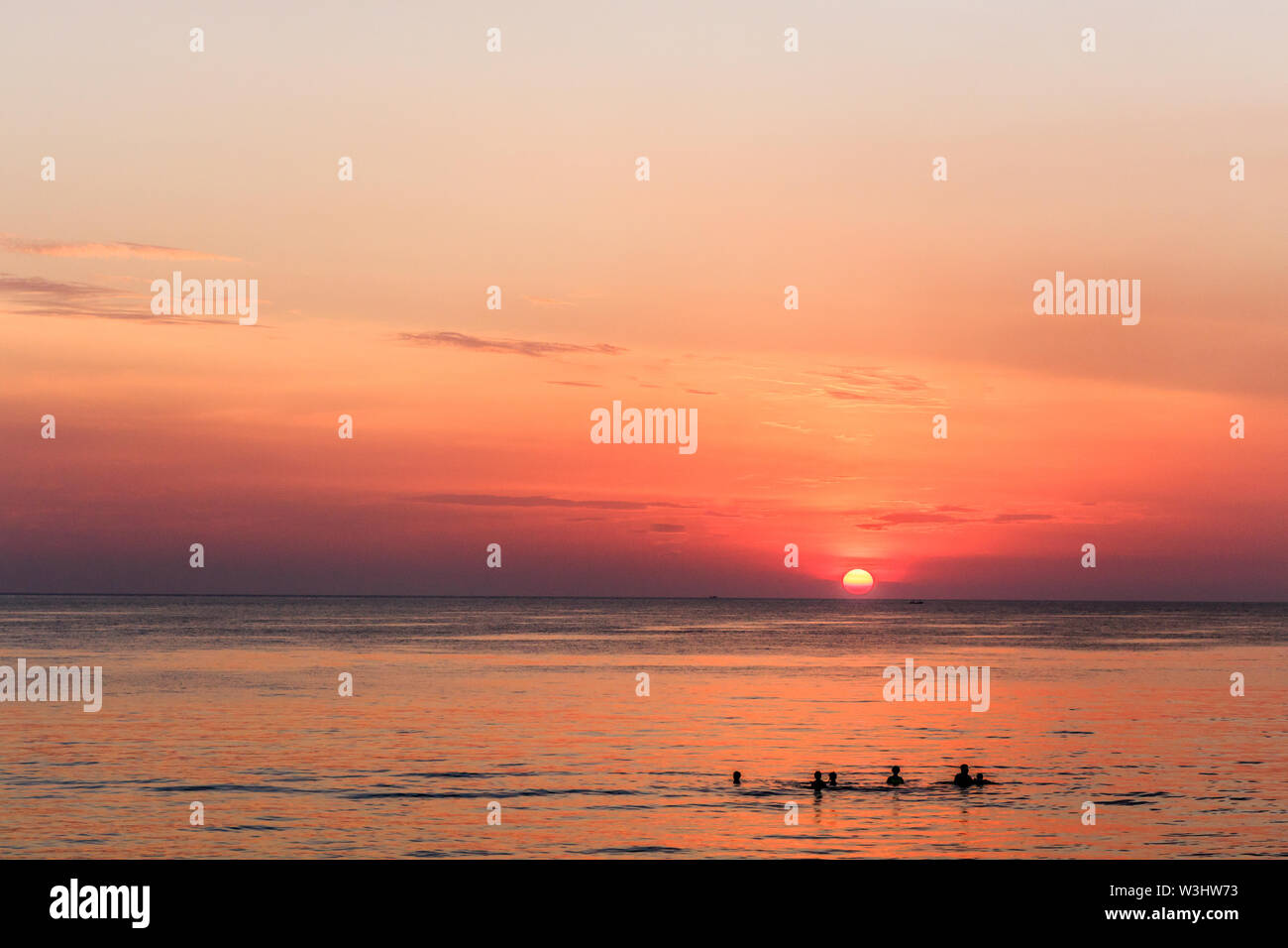 La gente di nuoto in mare al tramonto. Bang Tao Beach, Phuket, Tailandia Foto Stock