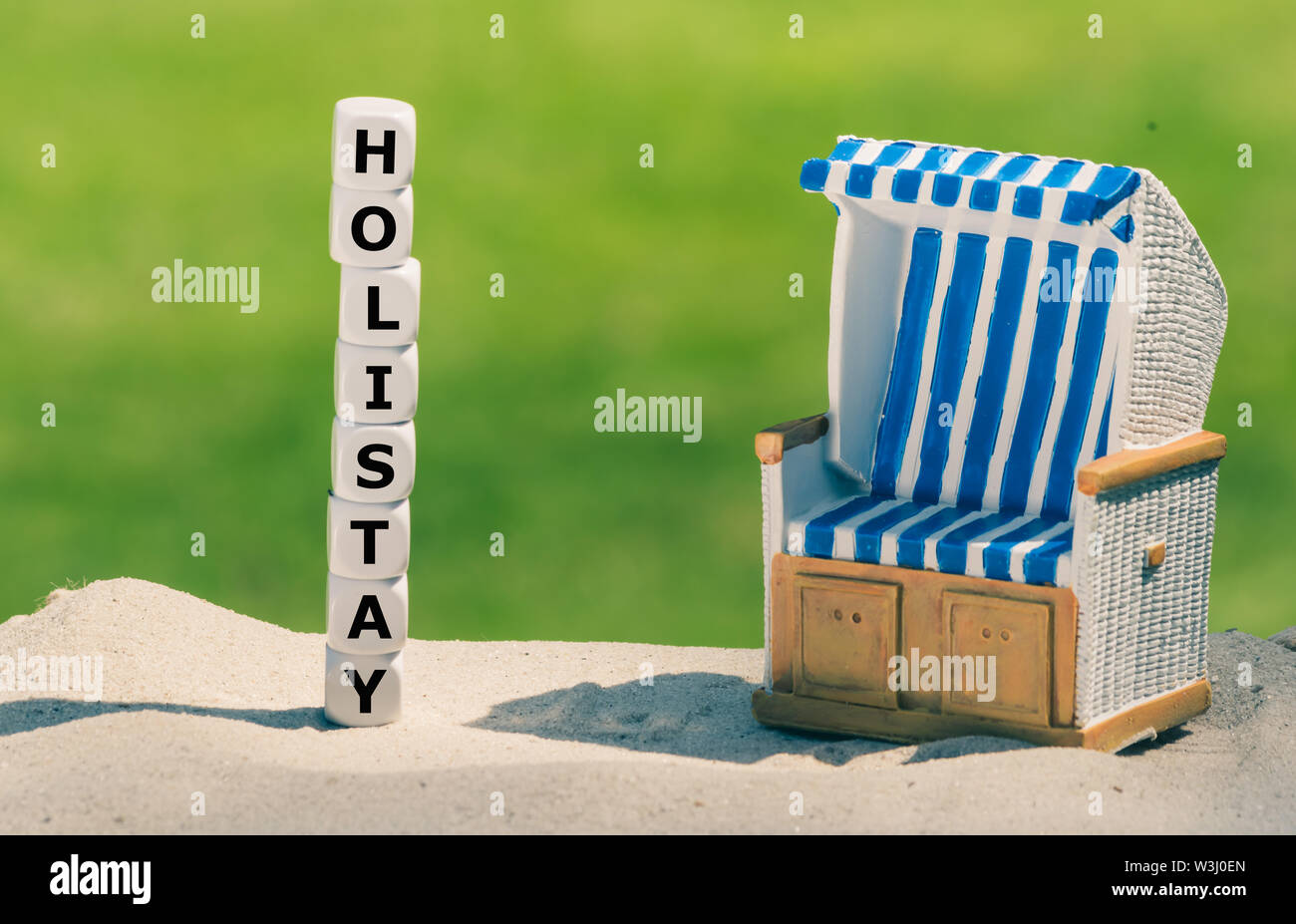 Vacanza a casa. Dadi forma la parola 'holistay' accanto a una sdraio sulla spiaggia. Foto Stock