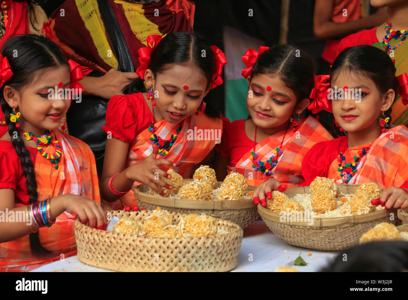 Giovani danzatori offrono i cesti di dolce tradizionale 'Moa' fatta di riso soffiato a 'Nabanna Utsab', il bengali harvest festival. Dacca in Bangladesh Foto Stock