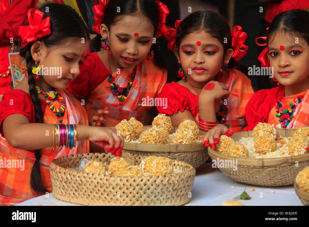 Giovani danzatori offrono i cesti di dolce tradizionale 'Moa' fatta di riso soffiato a 'Nabanna Utsab', il bengali harvest festival. Dacca in Bangladesh Foto Stock