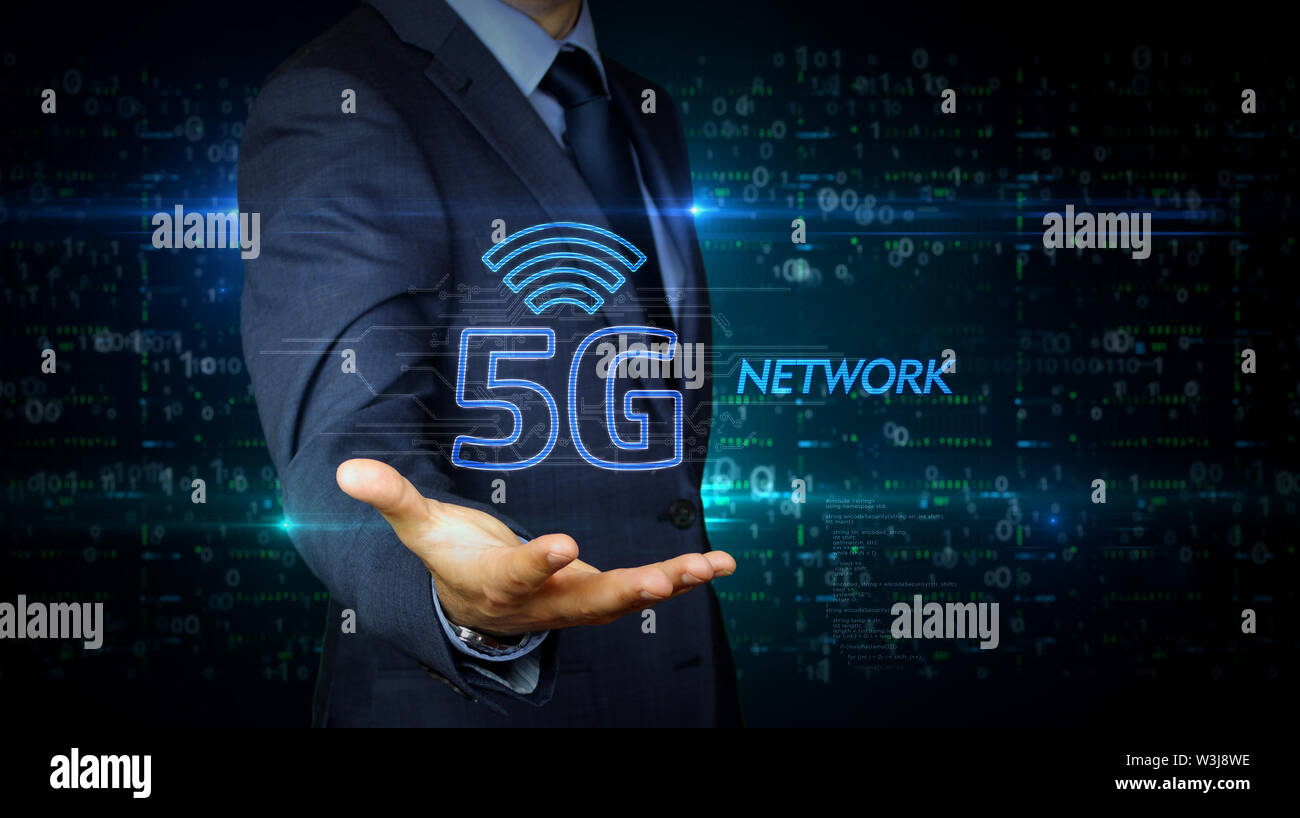 Un imprenditore in un vestito e lo schermo con 5G ologramma. Uomo con mano sul display virtuale di interfaccia. Rete wireless, la comunicazione mobile, dati tra Foto Stock