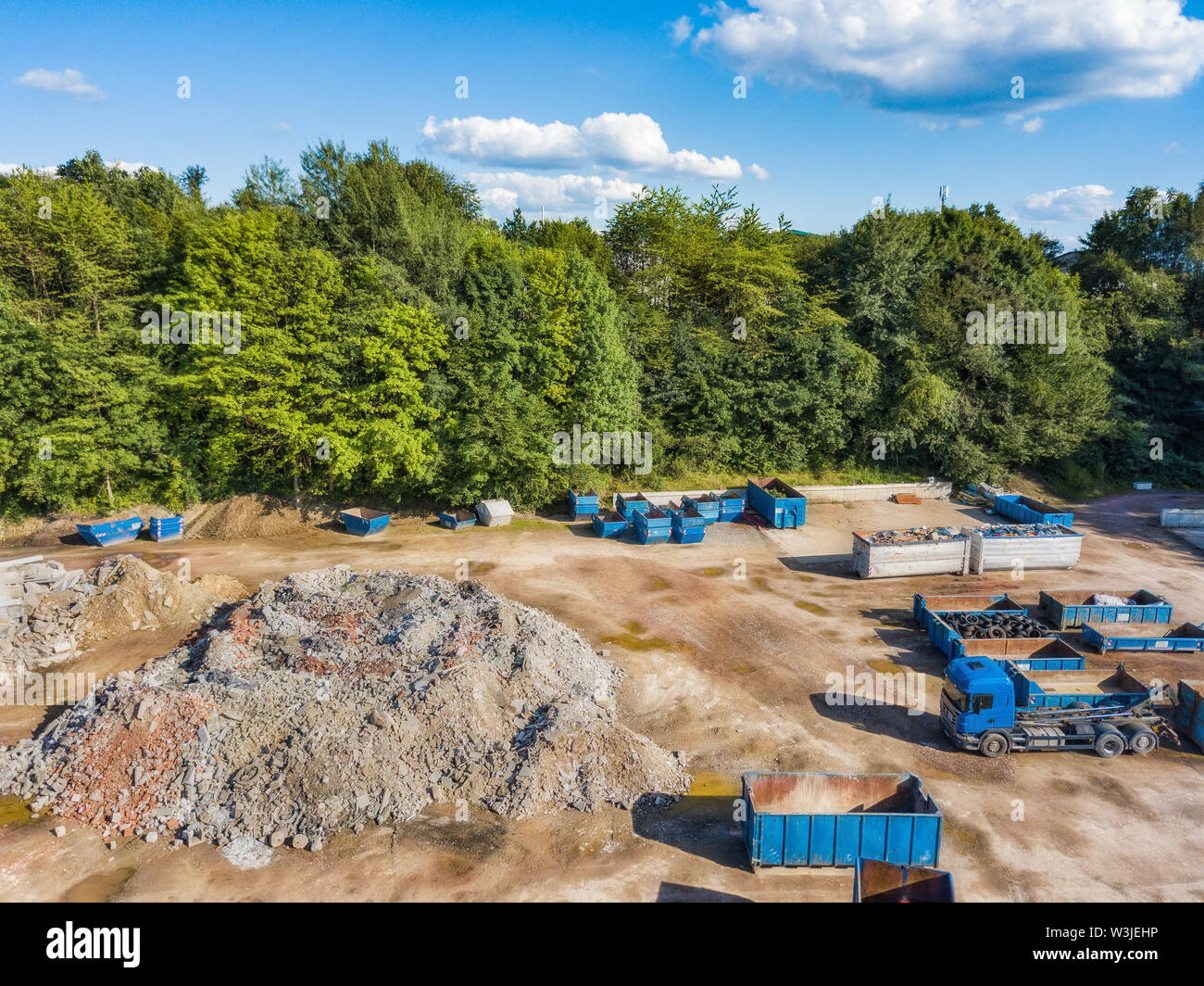 Vista aerea di un cantiere di riciclaggio con camion e container. Foto Stock