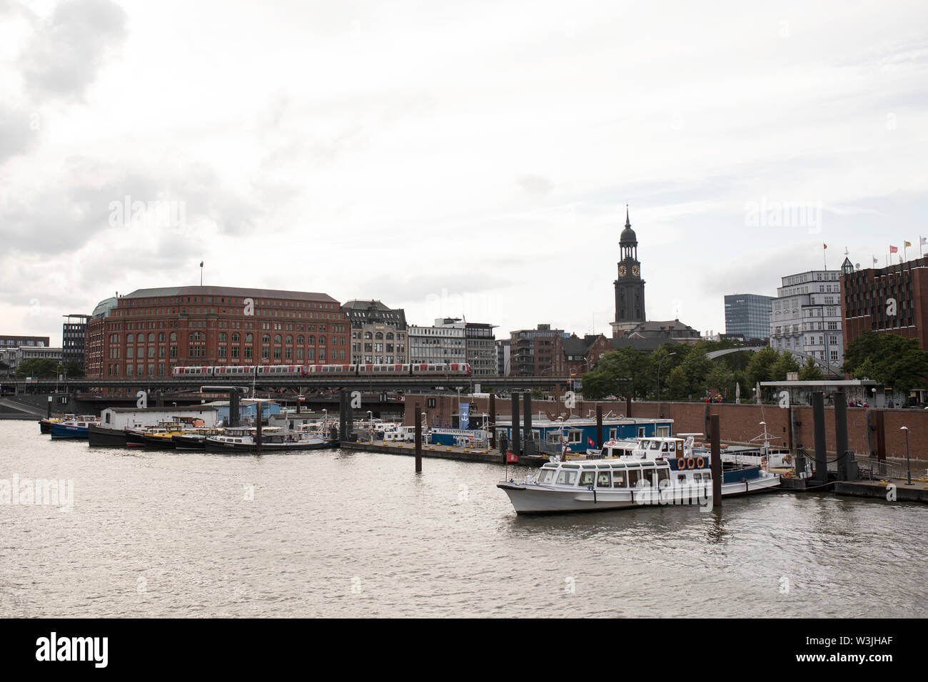 Un treno U-Bahn attraversa il ponte otto-sill-Brücke nella zona di Hafencity di Amburgo, in Germania, con la chiesa di San Michele sullo sfondo. Foto Stock