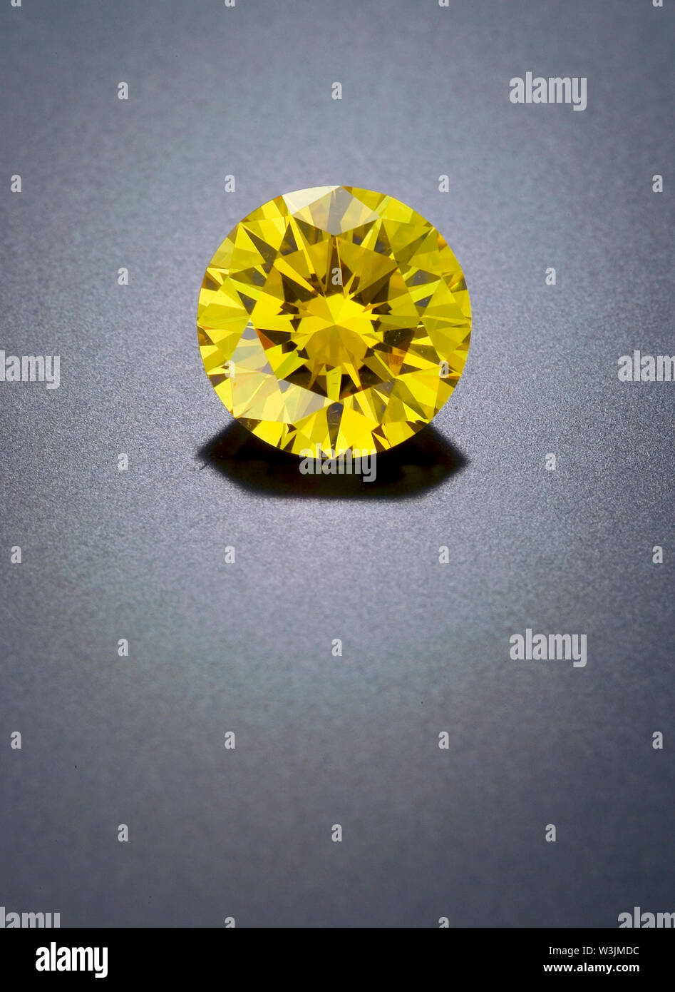 Un solitare, allentati, pulire, sfaccettata giallo canarino, round diamond siede su un refective sfondo nero. Foto Stock