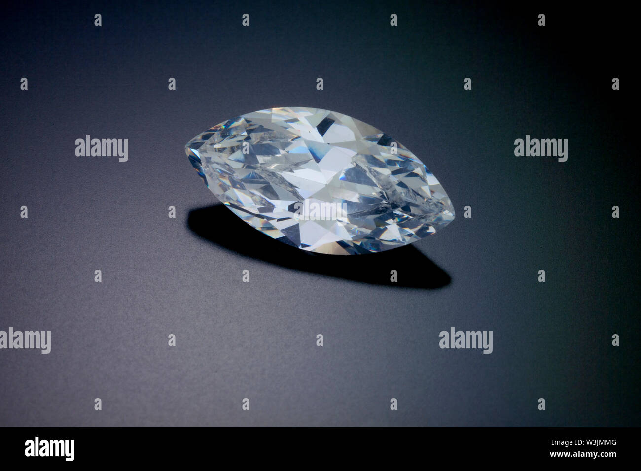Un marquise sfaccettato taglio del diamante si siede su un nero sfondo riflettente. Foto Stock