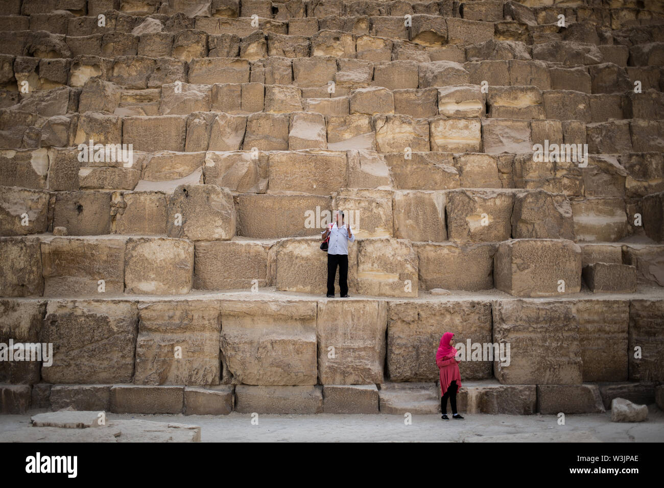 Giza in Egitto. 16 Luglio, 2019. Un uomo egiziano e sua figlia stare ai piedi della piramide di Khufu, conosciuta anche come la Grande Piramide sull'altopiano di Giza. La piramide di Khufu è la più antica delle sette meraviglie del mondo antico e il solo a rimanere in gran parte intatto. Credito: Oliver Weiken/dpa/Alamy Live News Foto Stock