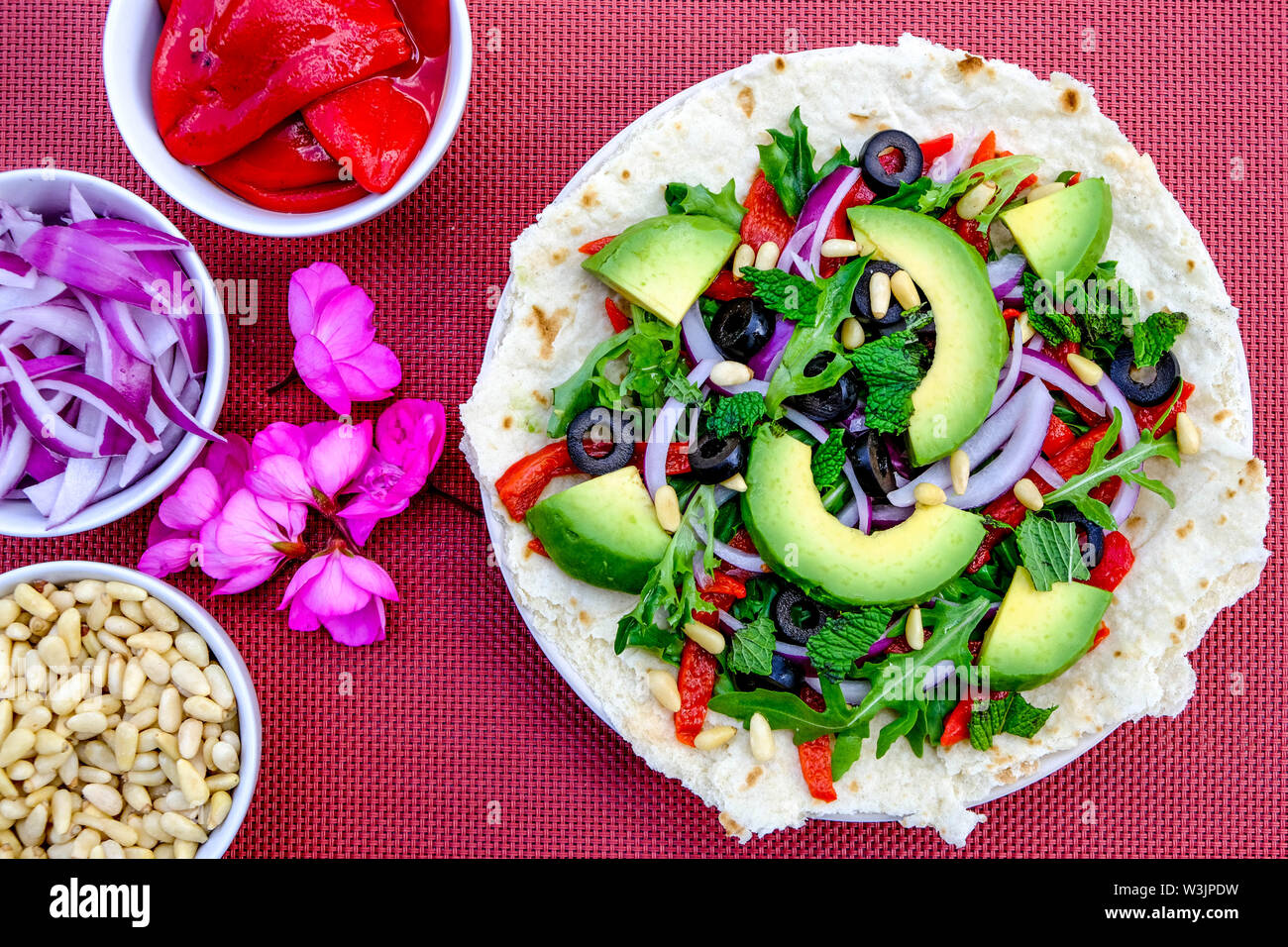 Vegetariano sana insalata di avocado su una base per pizza con le cipolle rosse, peperoni rossi menta e olive nere Foto Stock
