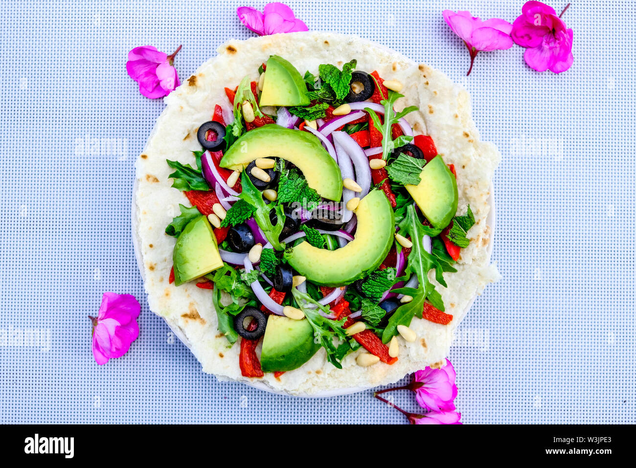 Vegetariano sana insalata di avocado su una base per pizza con le cipolle rosse, peperoni rossi menta e olive nere Foto Stock