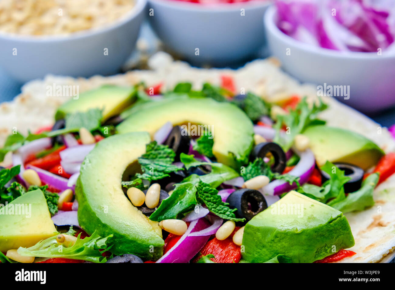Vegetariano sana insalata di avocado su una base per pizza con le cipolle rosse, peperoni rossi menta e olive nere Foto Stock