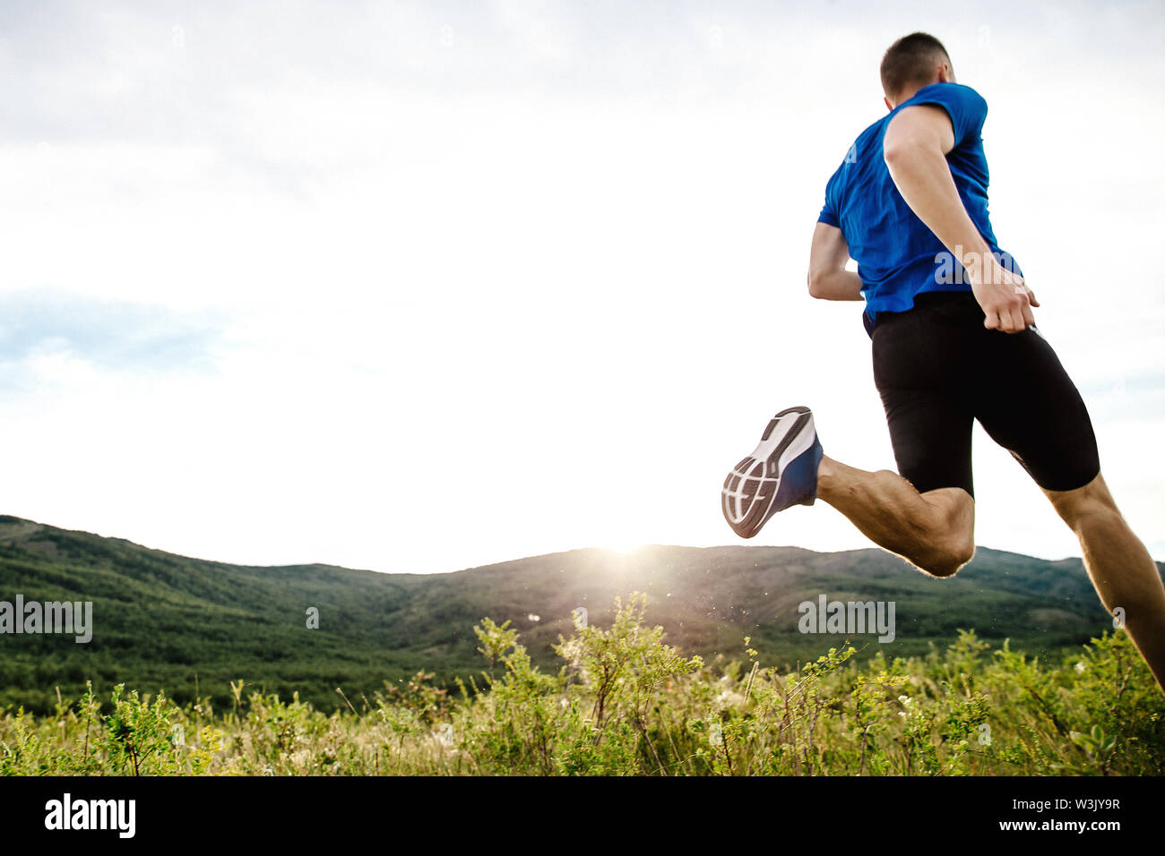 Atleta runner dynamic in esecuzione su estate montagna altopiano motley erba nel tramonto Foto Stock