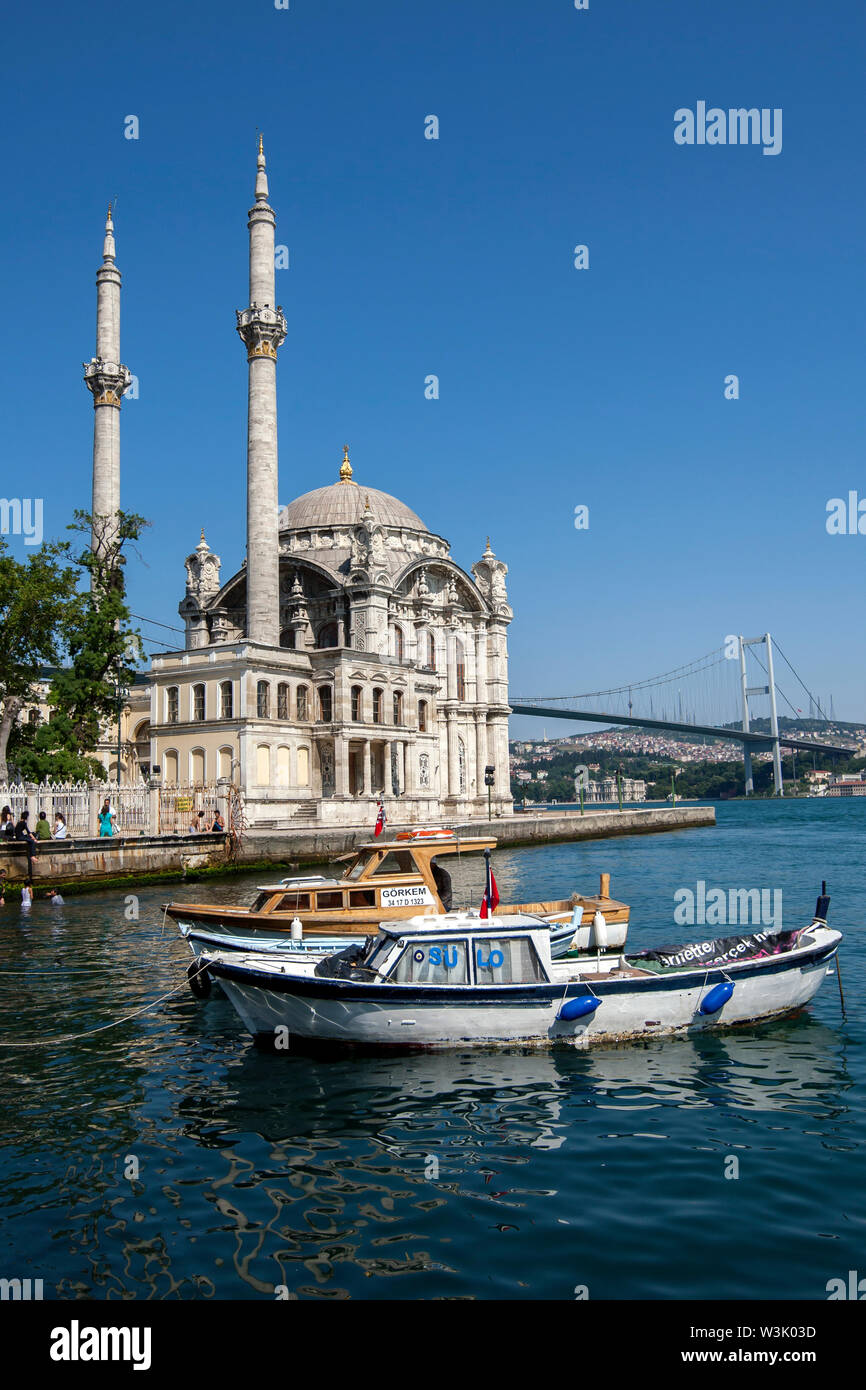 La pesca barche ormeggiate nel Bosforo adiacente all'Ortakoy Camii (moschea) a Ortakoy ad Istanbul in Turchia. Foto Stock
