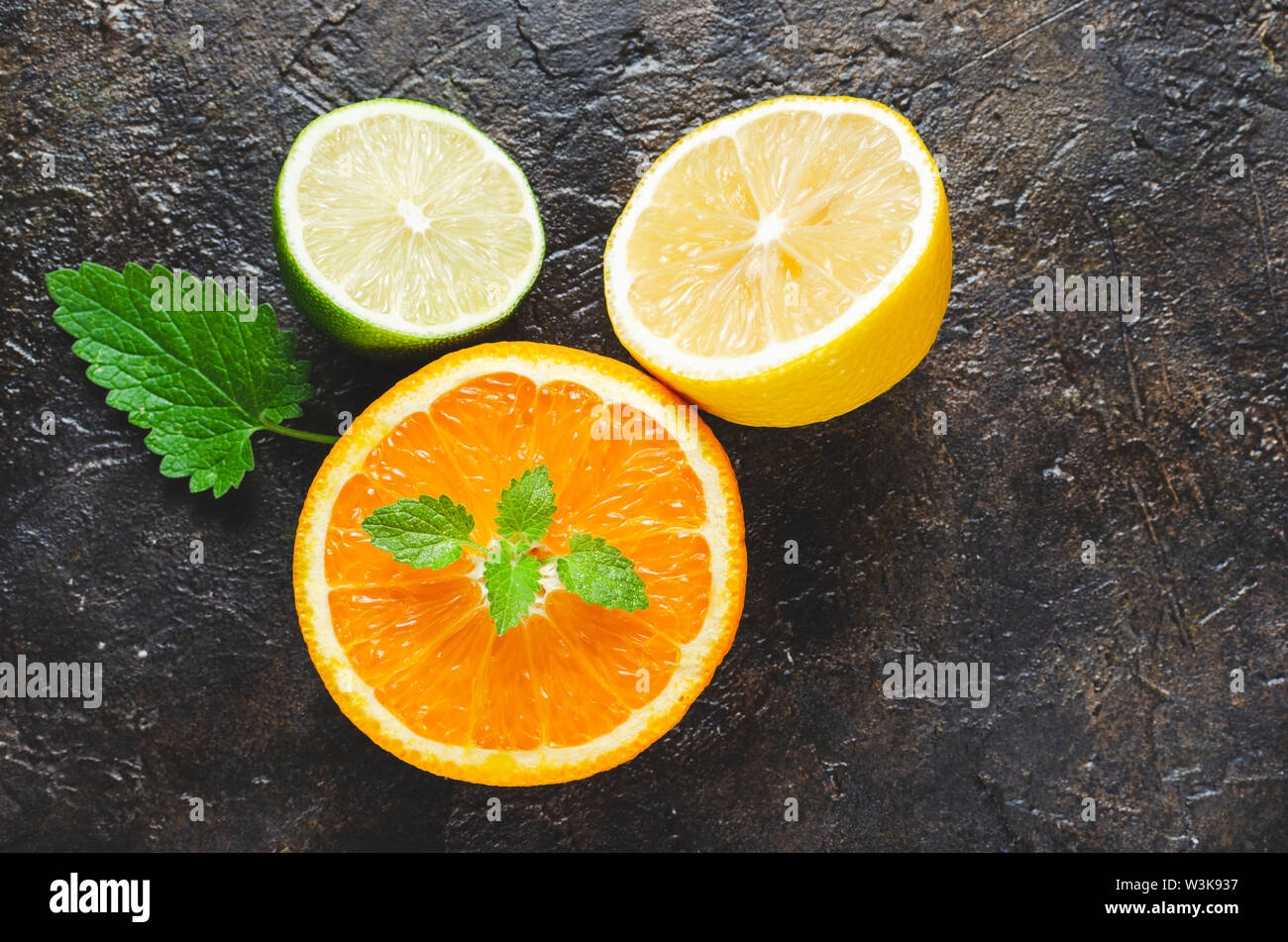 Fette di arancia e limone e lime con foglie di menta su un sfondo di calcestruzzo. Foto Stock