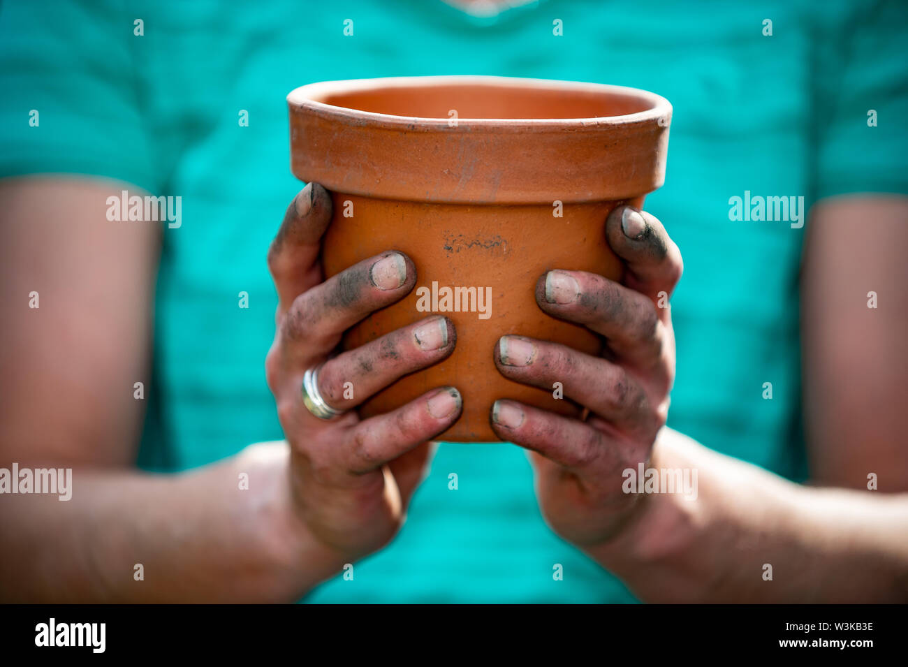 Giardiniere femmina azienda argilla vaso di fiori con mani fangose Foto Stock