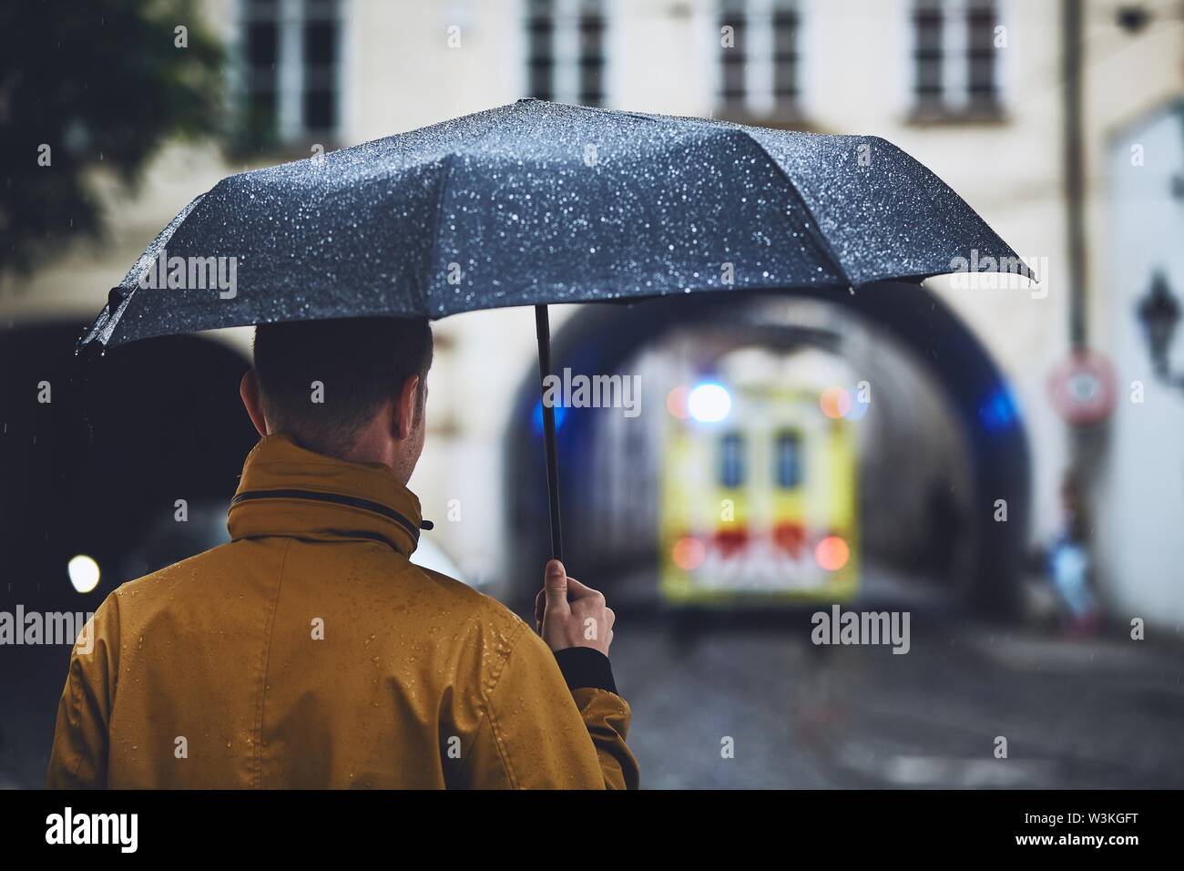 Uomo con ombrello guardando lasciando ambulanza del servizio di emergenza medica in giorno di pioggia. Praga, Repubblica Ceca Foto Stock
