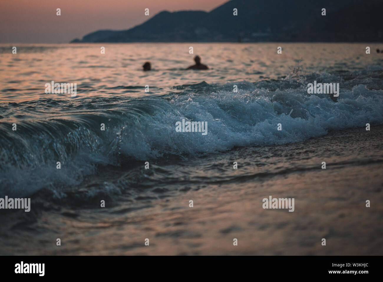 La gente di nuoto in mare al tramonto di sera, Cleopatra beach in Alanya, Turchia, distretto di Antalya Foto Stock