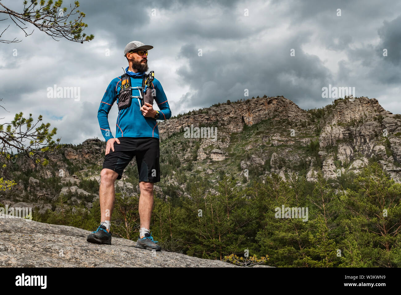 Runner maschio in piedi su una roccia in montagna. Atleta corre in montagna  tra le rocce. Uomo in maglia blu e pantaloncini neri all'aperto di  formazione Foto stock - Alamy