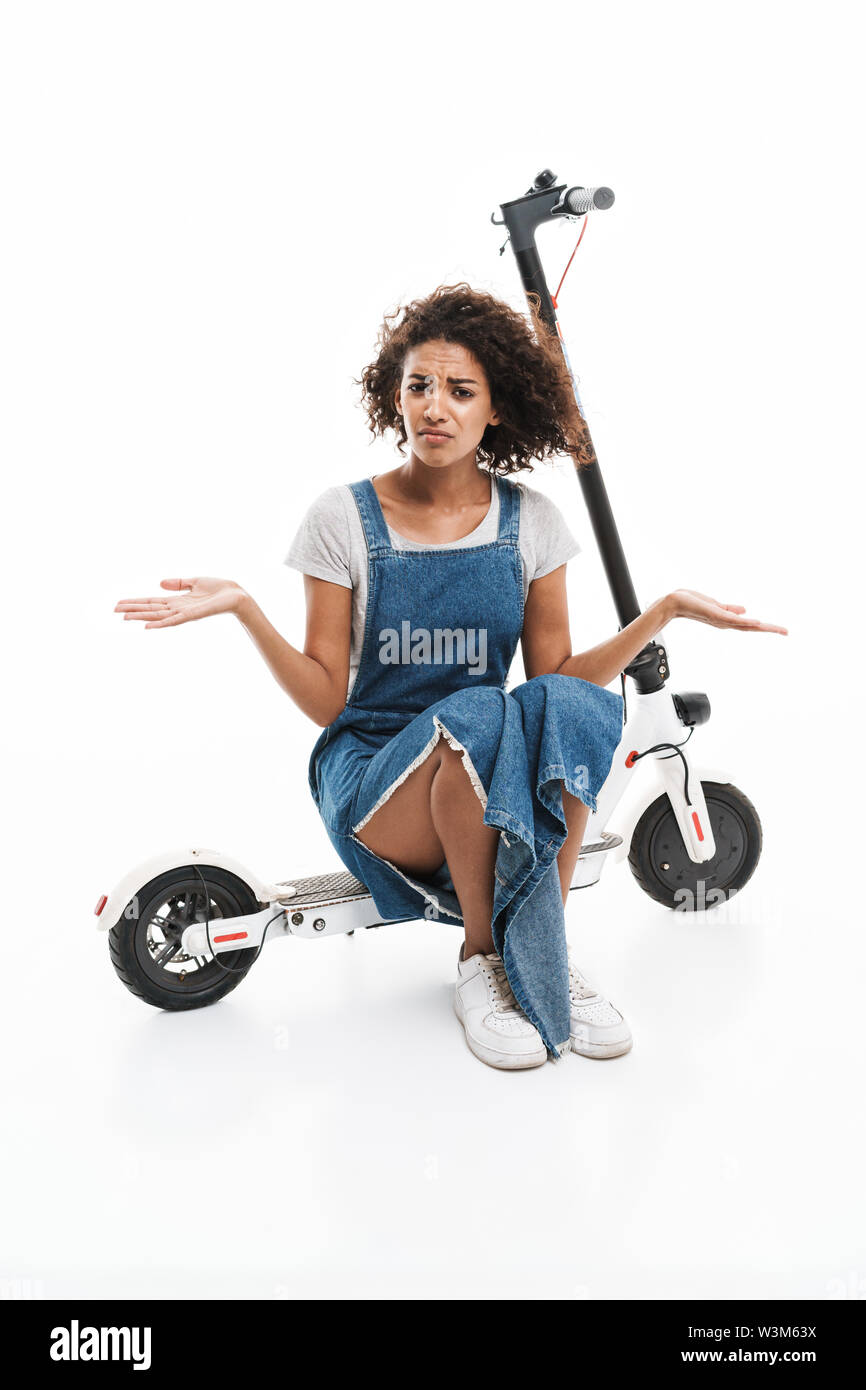 Immagine di orinato americano africano donna esprimere il proprio sdegno seduti su scooter elettronico isolato su sfondo bianco Foto Stock