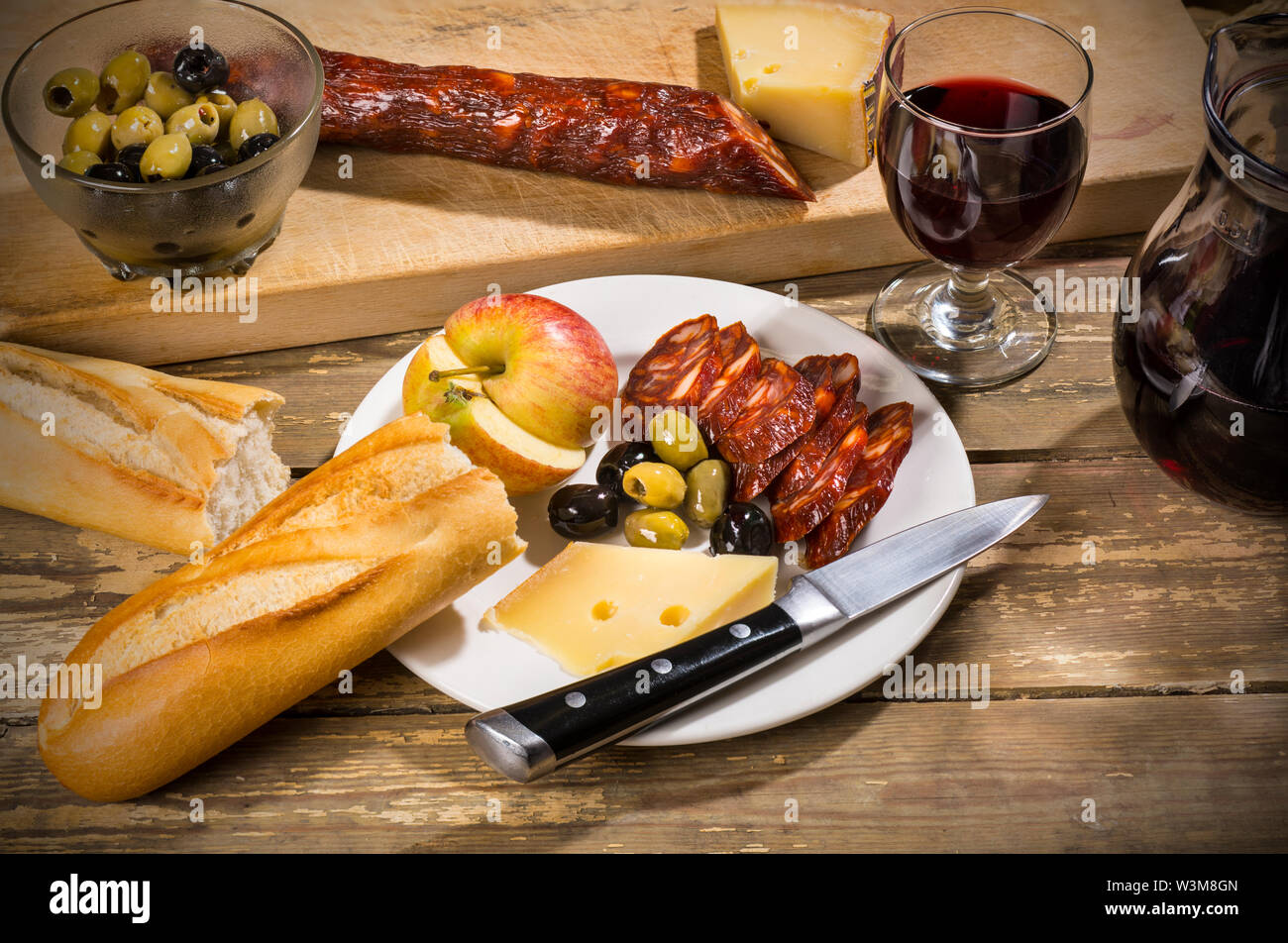 Plowman pranzo in Spagna: il chorizo, formaggio di capra, olive, Apple, pane e un bicchiere di vino Foto Stock