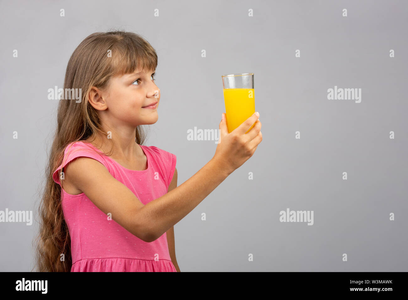 Una ragazza tiene un bicchiere di succo di frutta in mano e guarda lo spazio vuoto sulla destra Foto Stock