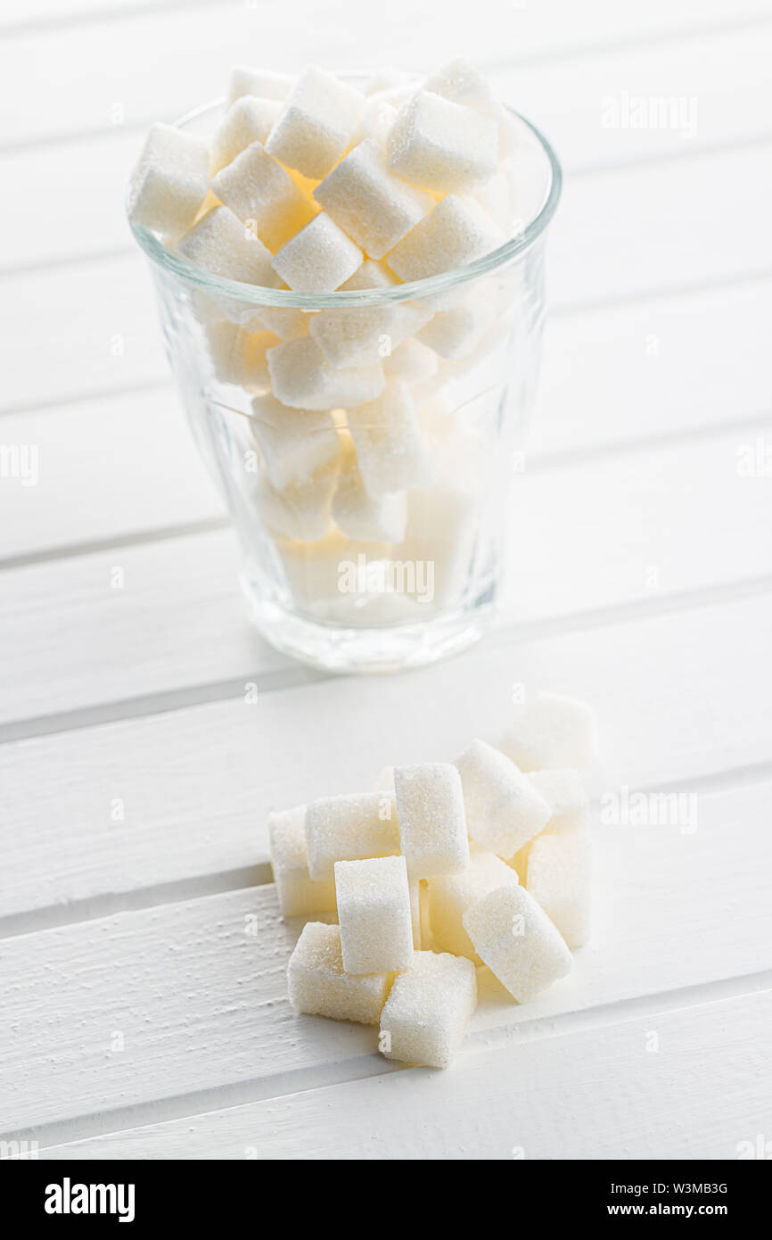 Zucchero bianco i cubi su tavolo bianco. Foto Stock