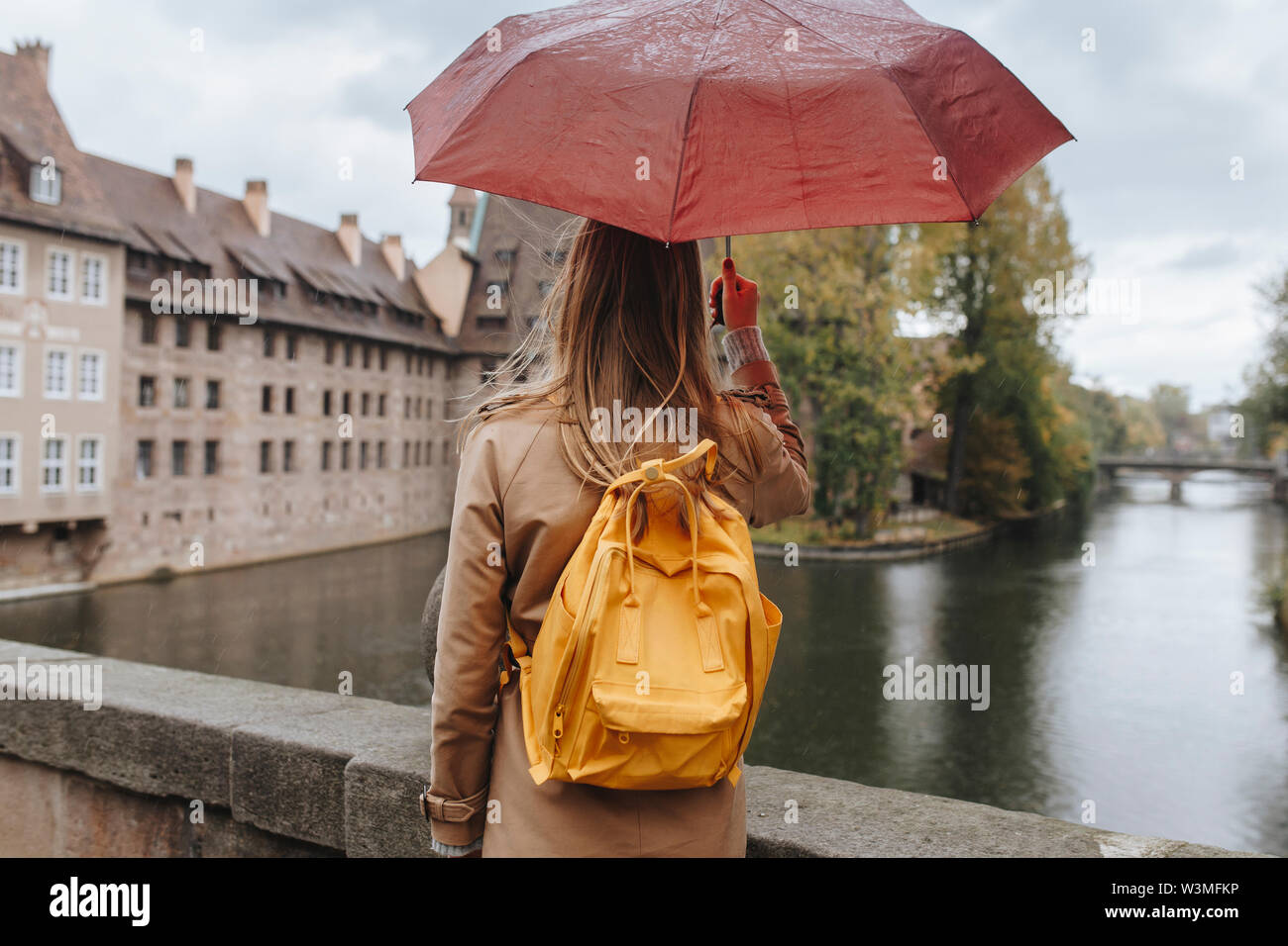 Donna che indossa uno zaino holding ombrello da fiume a Norimberga, Germania Foto Stock