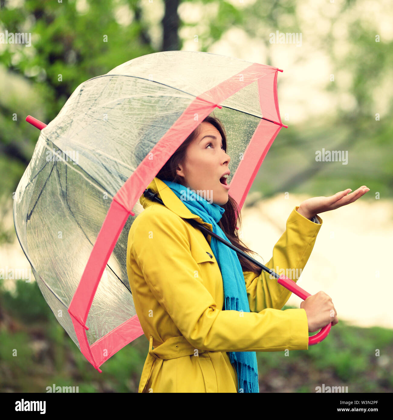 Ombrello donna in autunno eccitati sotto la pioggia caduta sul giorno.giovane e bella donna che indossa un impermeabile sorpreso ed entusiasmato sotto la pioggia. Razza mista asiatica ragazza caucasica nel suo 20s a piedi nella foresta. Foto Stock