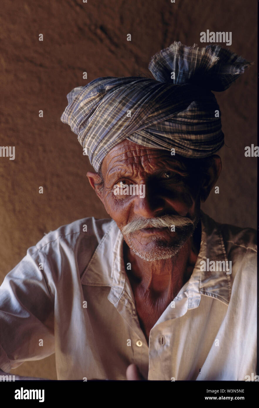 Un Sindhi uomo si siede fuori di casa sua in Mithi, un villaggio nel deserto Tharparkar regione della provincia del Sindh, in Pakistan. Luglio 10, 2005. Foto Stock