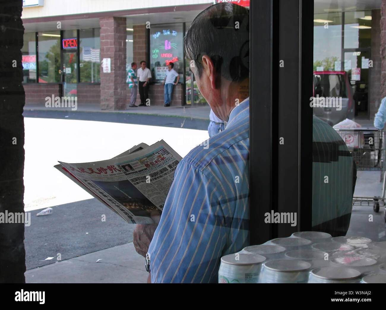 West Hartford, CT, Stati Uniti d'America. Lug 2015. Vista attraverso una finestra di un immigrato asiatico la lettura di un quotidiano locale nella sua lingua nativa. Foto Stock