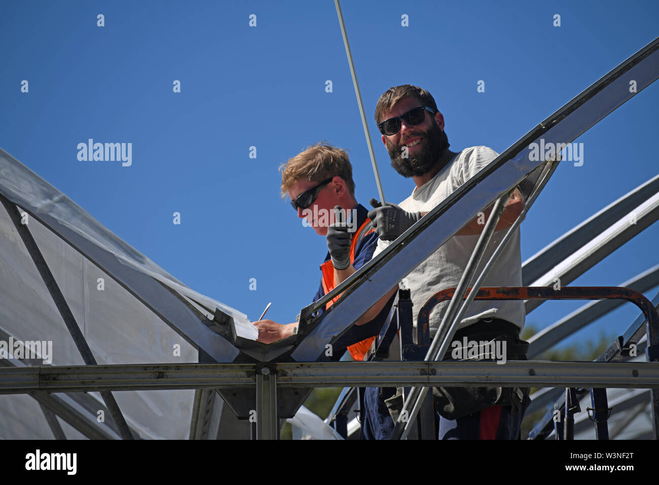 Greymouth, Nuova Zelanda, dicembre 12, 2018: Commercianti fissare la plastica su un nuovo tunnel house. Foto Stock