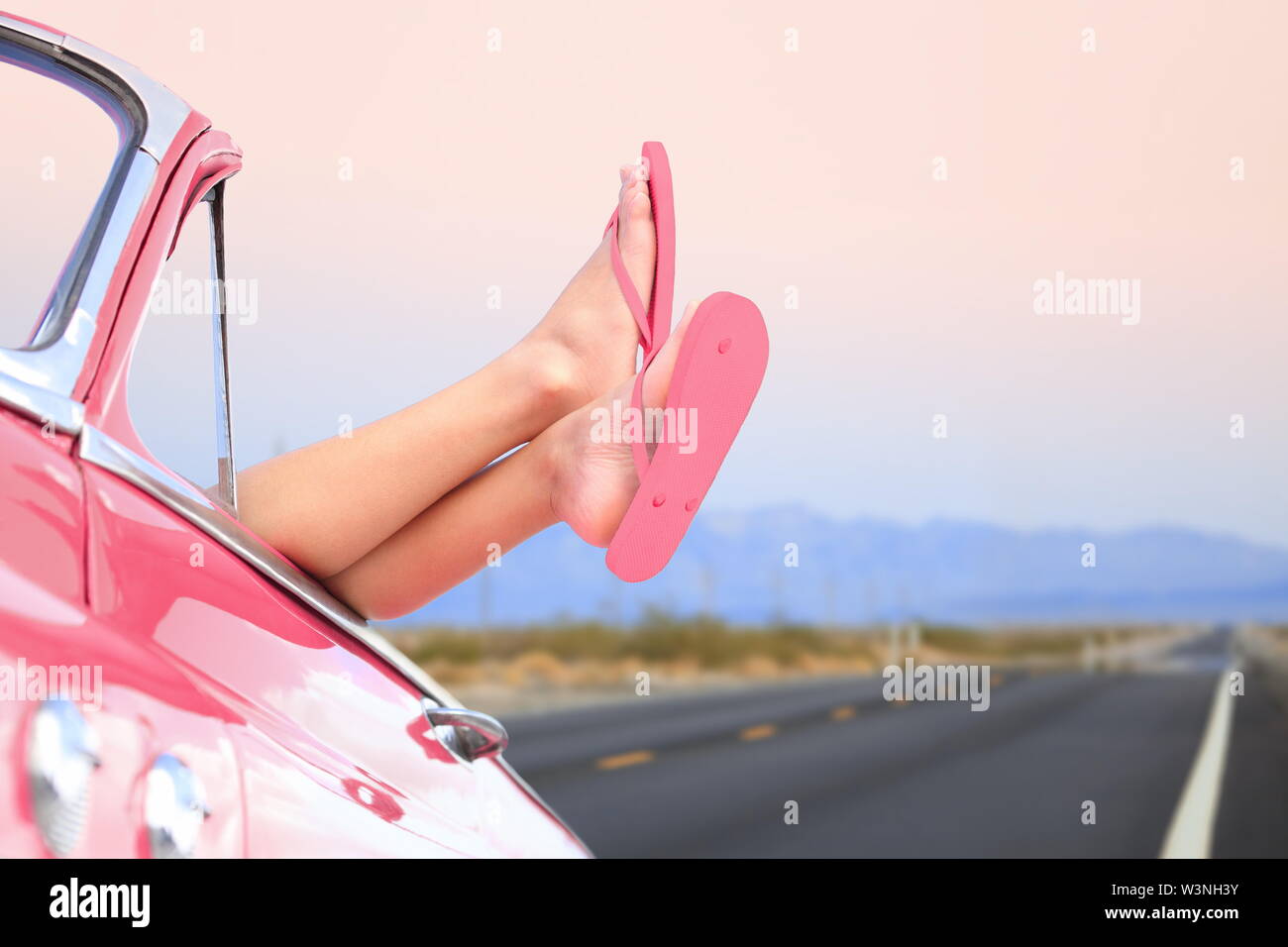 Freedom Car concetto di viaggio - donna rilassante con i piedi al di fuori della finestra nel raffreddare convertibile auto d'epoca. Ragazza rilassante godendo le vacanze gratis road trip. Foto Stock
