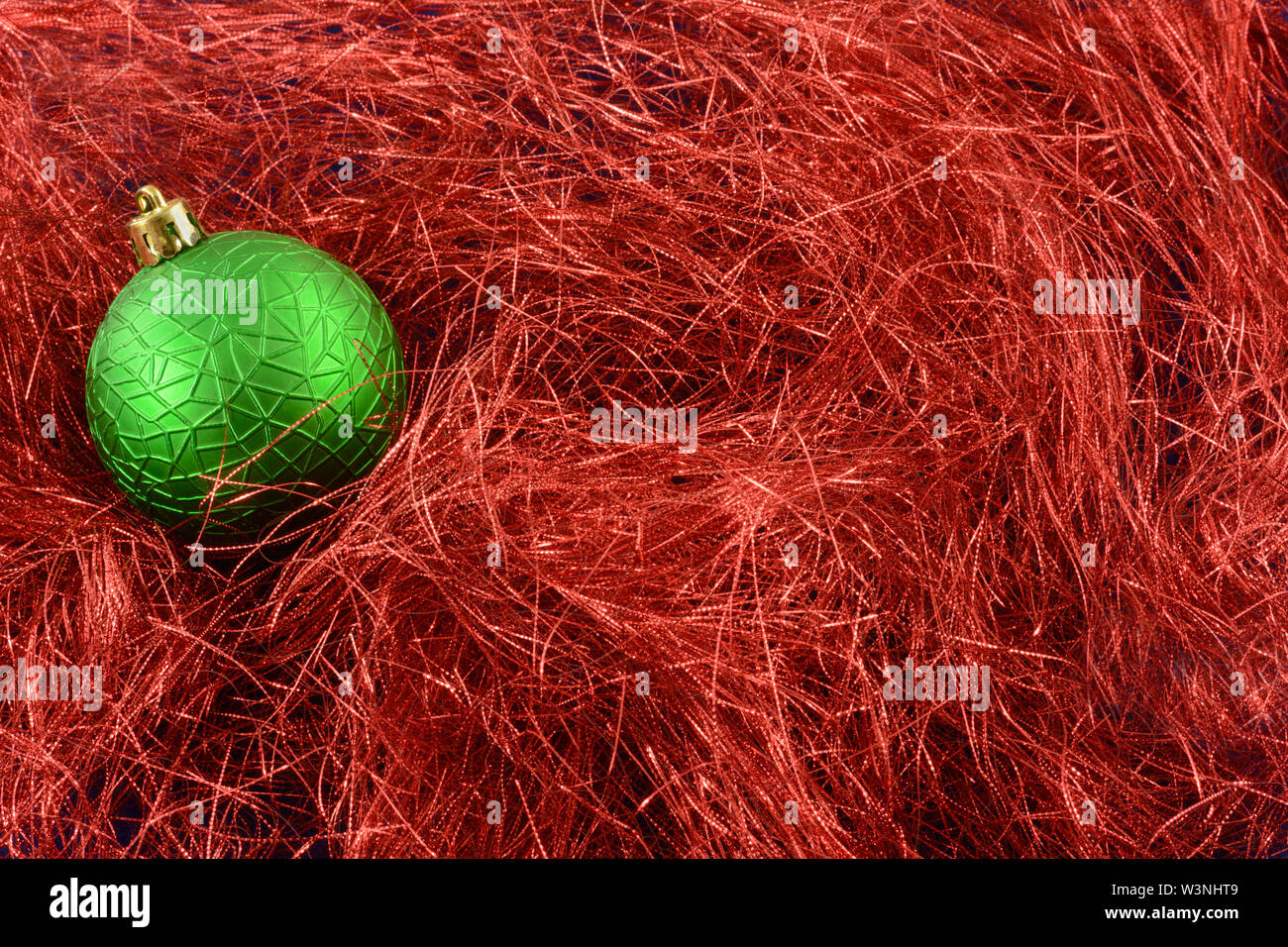 Verde di Natale ornamento sullo sfondo di sottili strisce di tinsel rosso Foto Stock