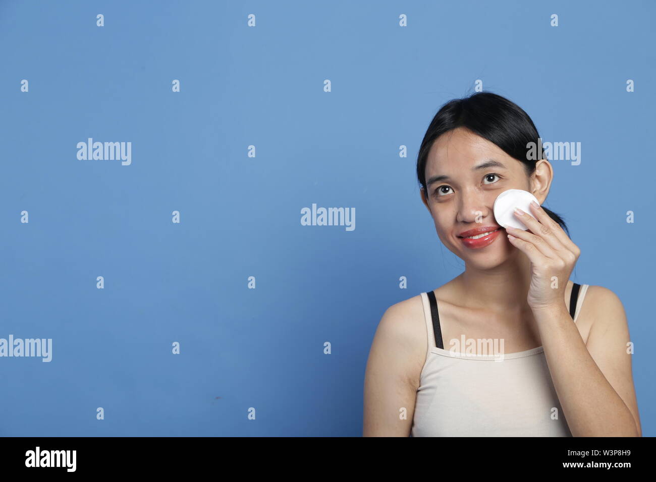 Bellezza giovani mix-gara donne asiatiche facendo pulizia attraverso la faccia e per la cura della pelle del viso e del make-up nella grande e luminosa colore di sfondo Foto Stock